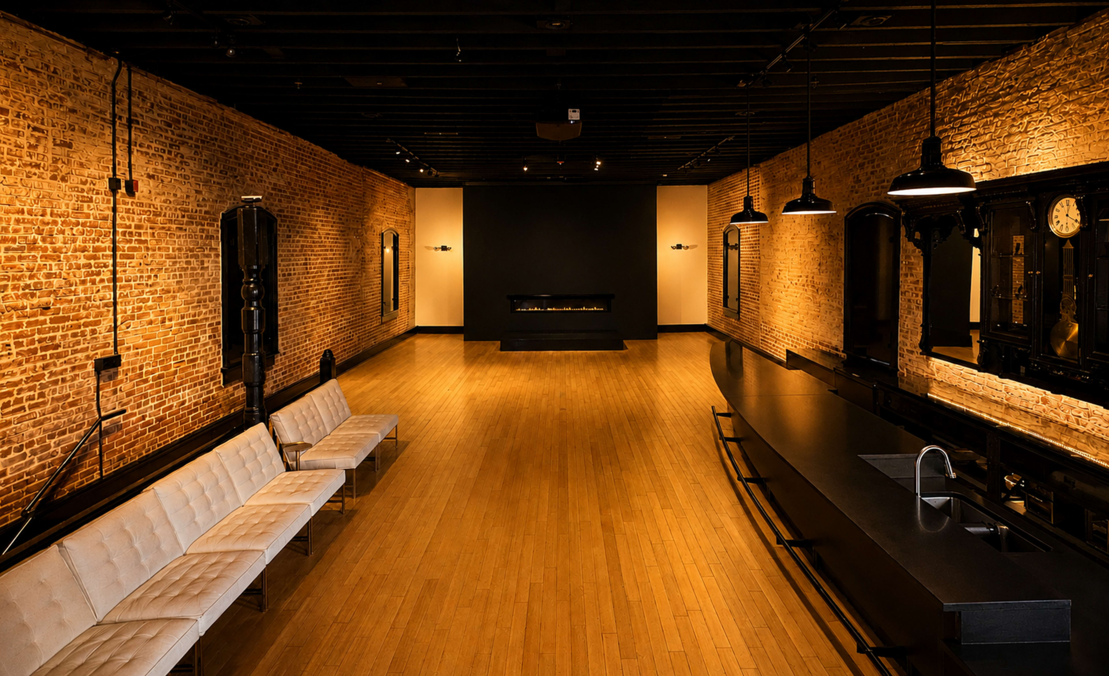 The image shows a spacious interior featuring exposed brick walls, a long bar counter, and a series of sleek seating options arranged along one side.