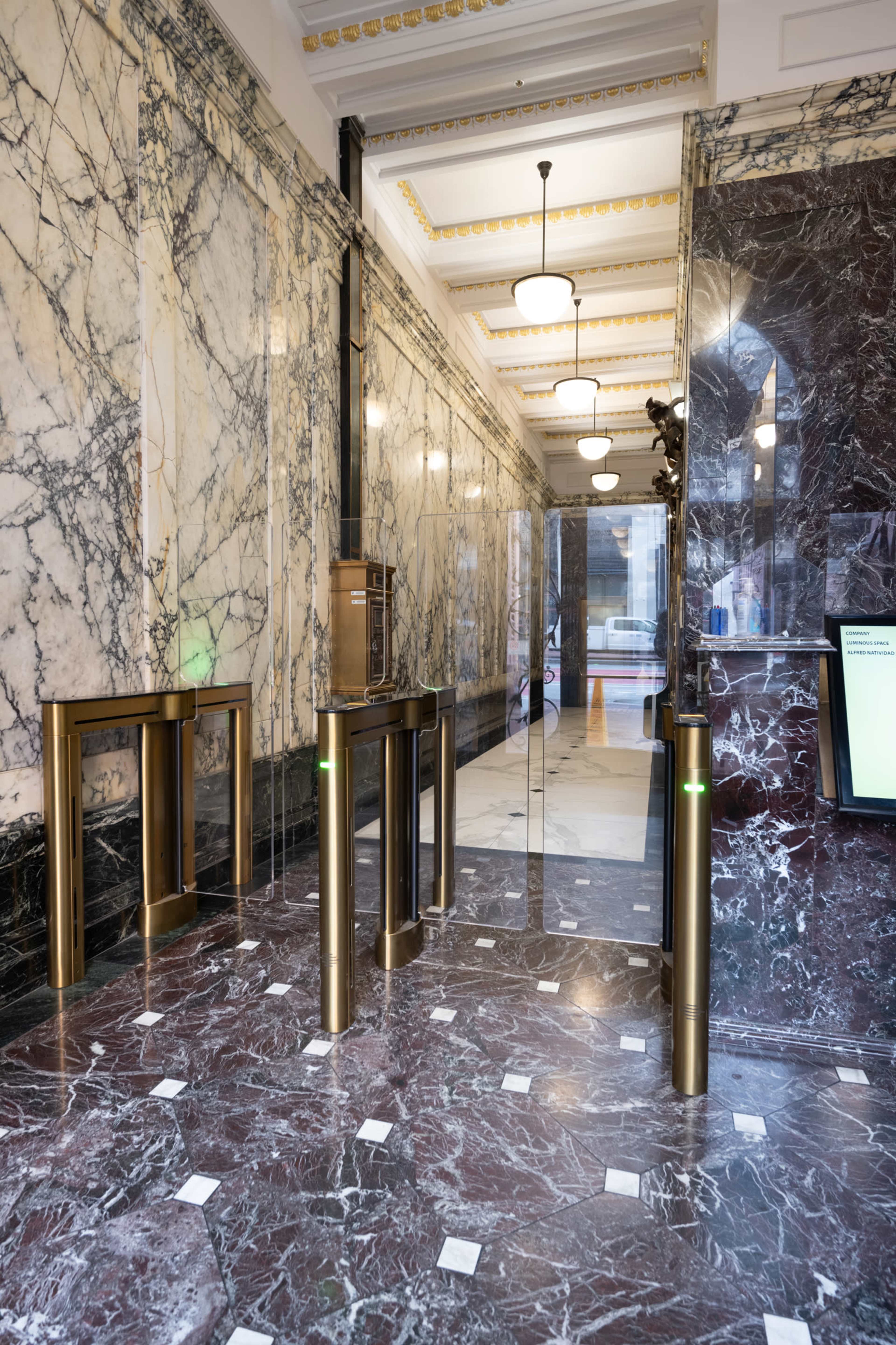 A marble-floored lobby with gold-accented turnstiles and decorative wall details.