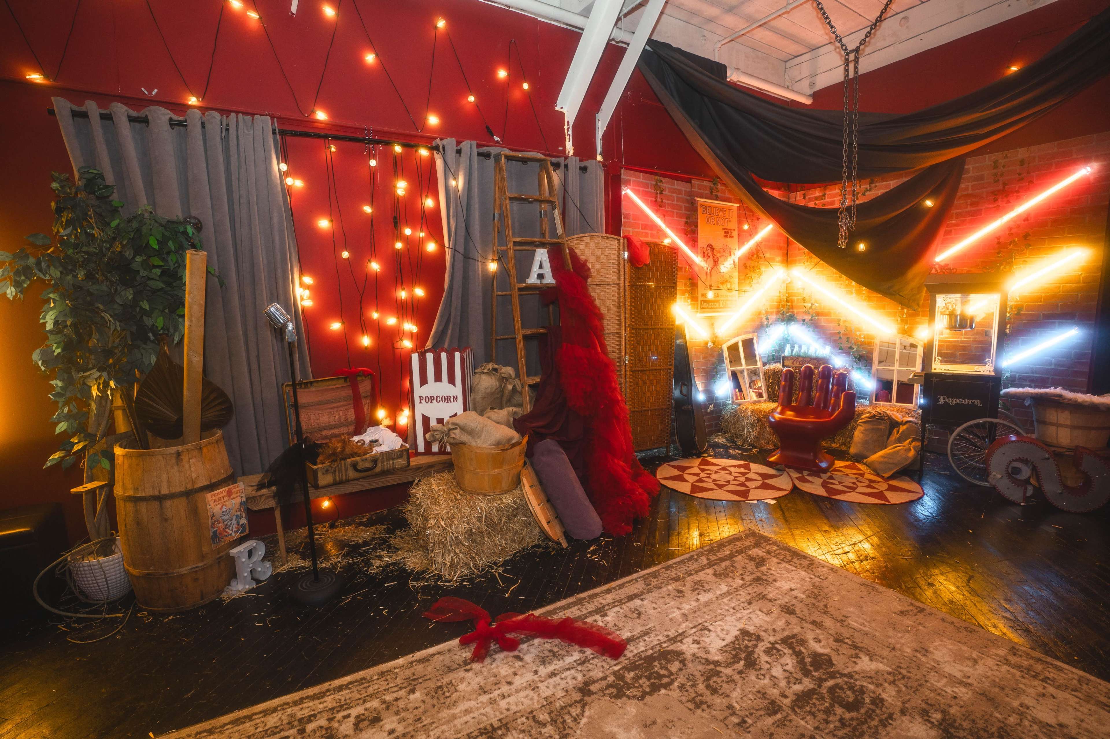 The scene features a room decorated with warm string lights, various props like barrels and hay, and colorful neon accents, creating a whimsical atmosphere.