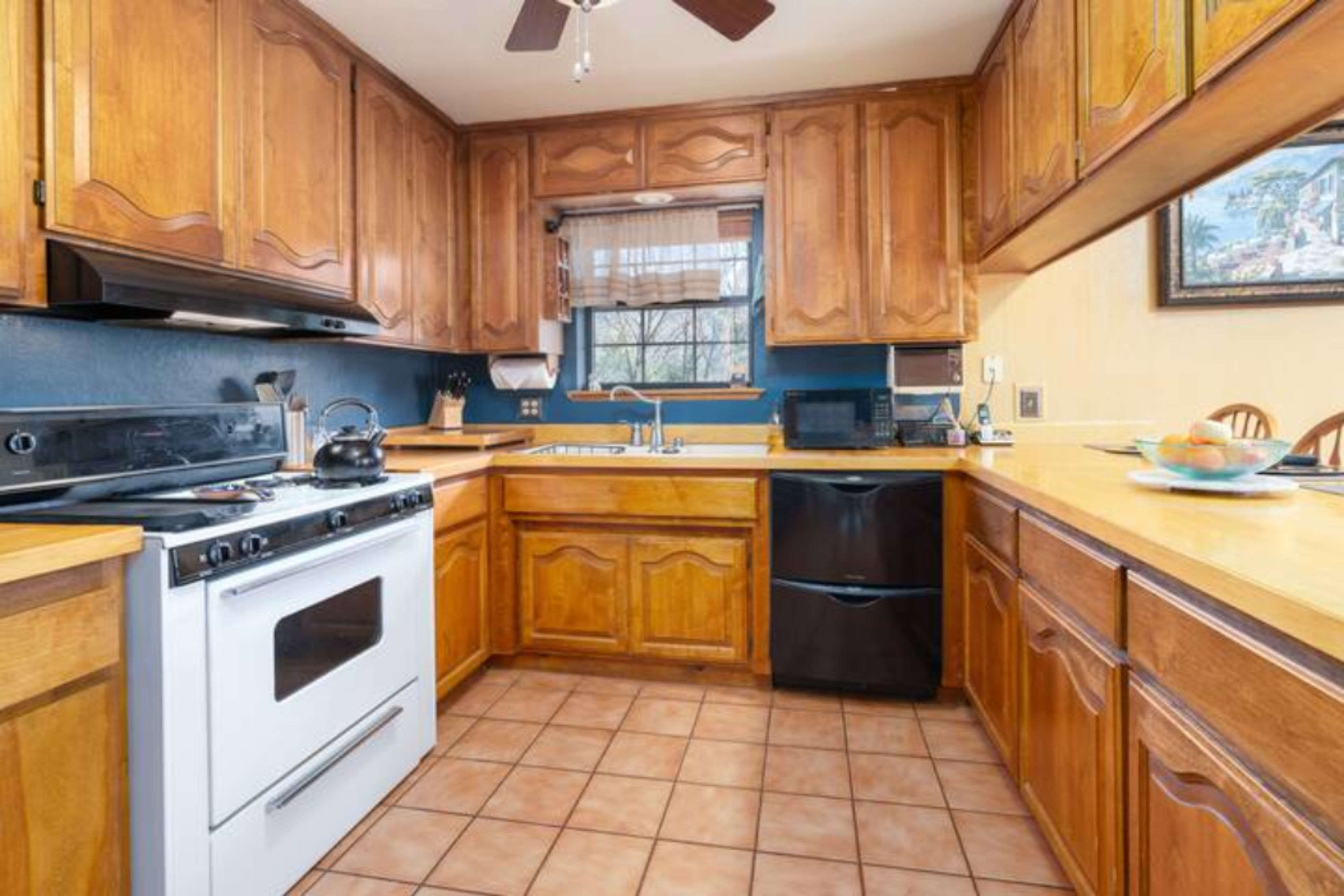 The kitchen features wooden cabinetry, a white stove, a black dishwasher, and tiled flooring.