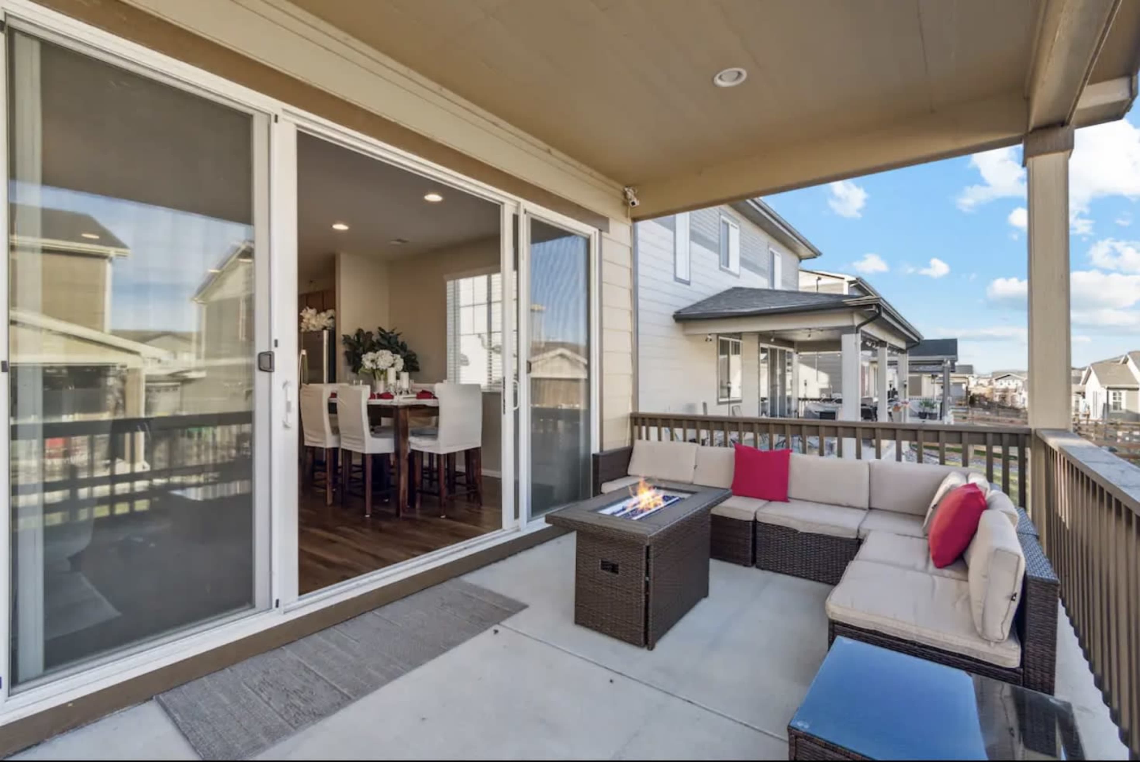 A patio features a seating area with a fire pit and sliding glass doors leading to an interior dining space.