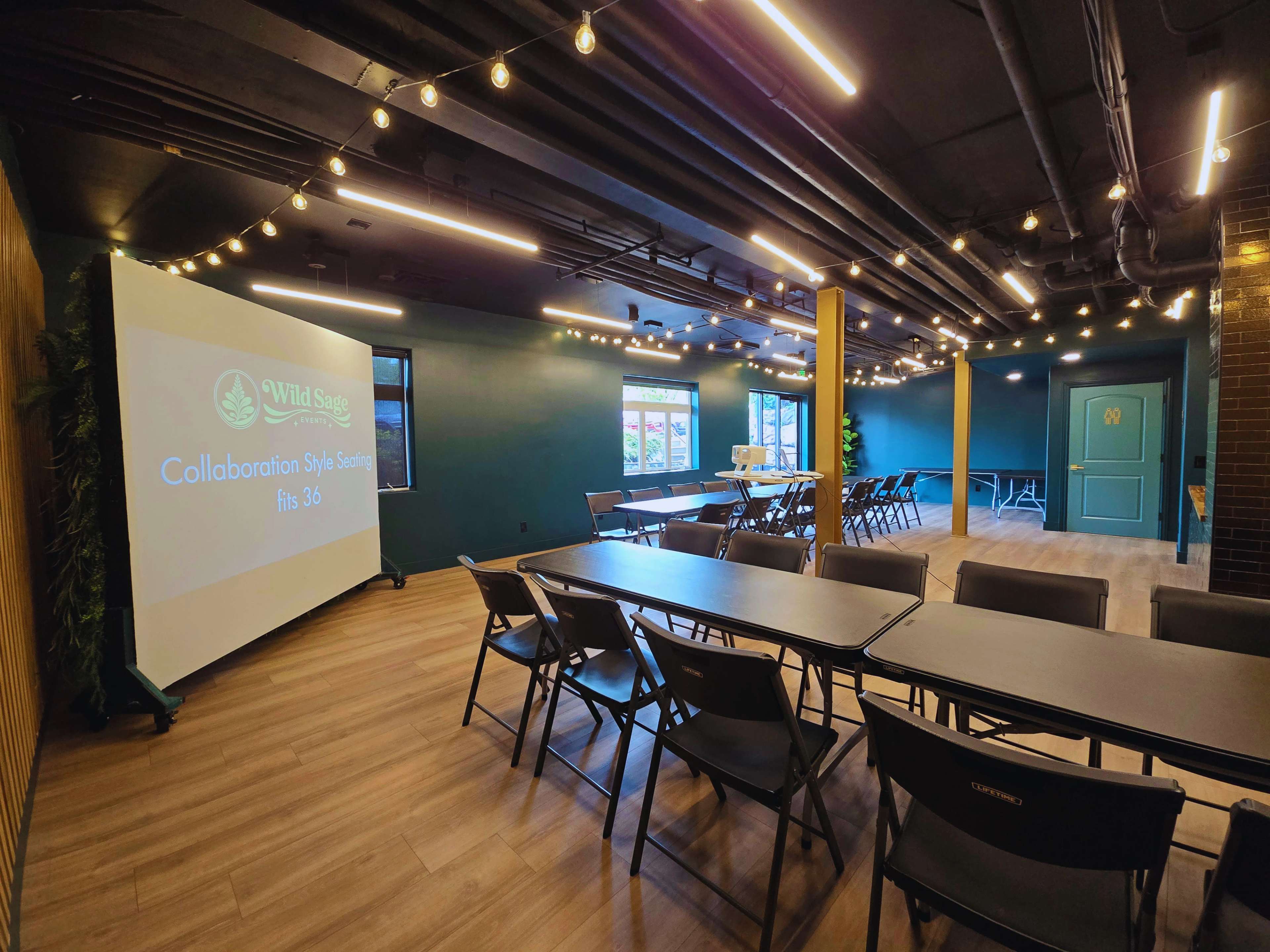 The image shows a modern meeting room with rows of folding chairs and tables, illuminated by string lights, featuring a large presentation screen displaying "Wild Sage" and "Collaboration Style Seating."