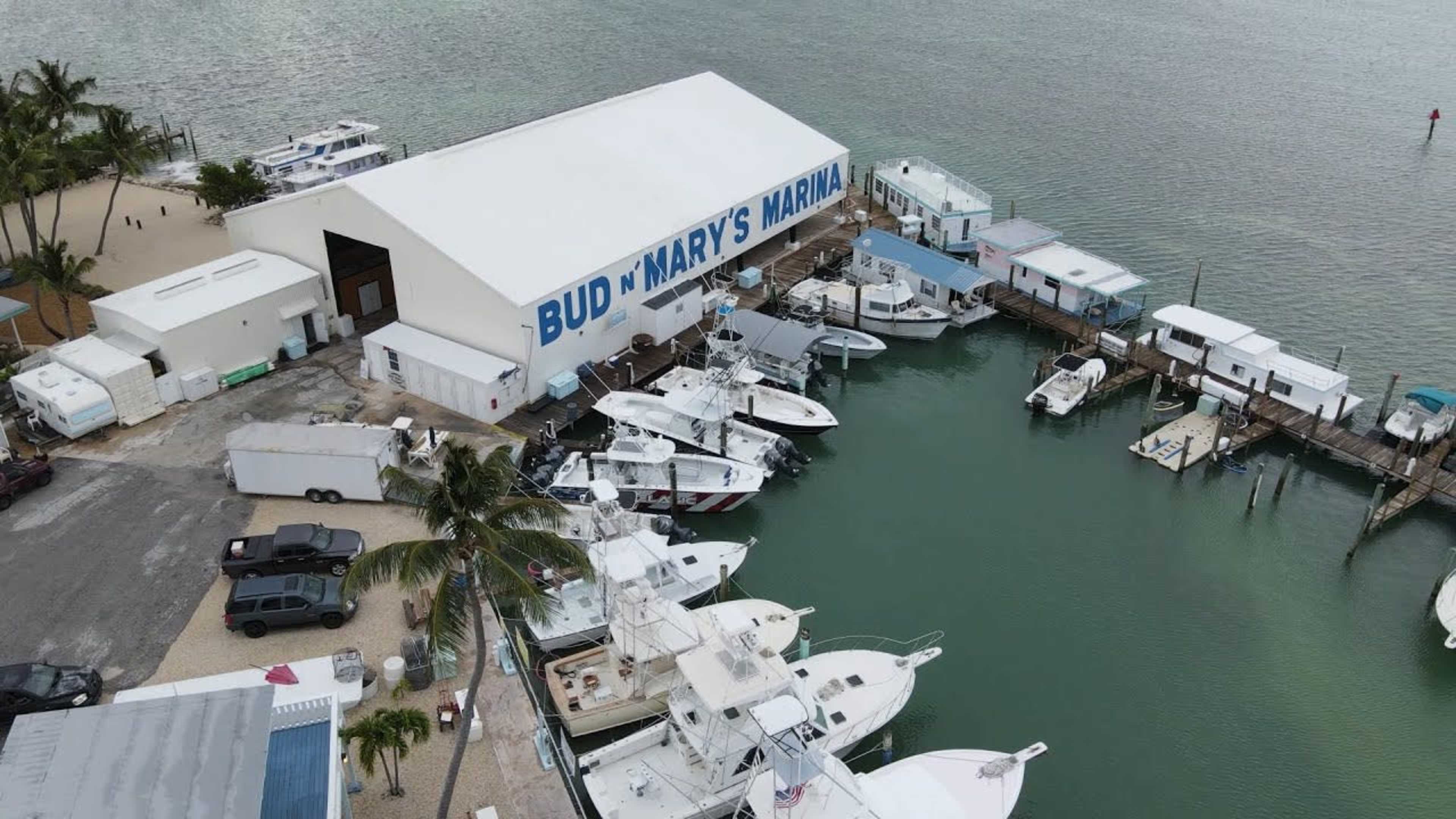 The image shows an aerial view of a marina with various boats docked alongside a building labeled "Bud n' Mary's Marina."