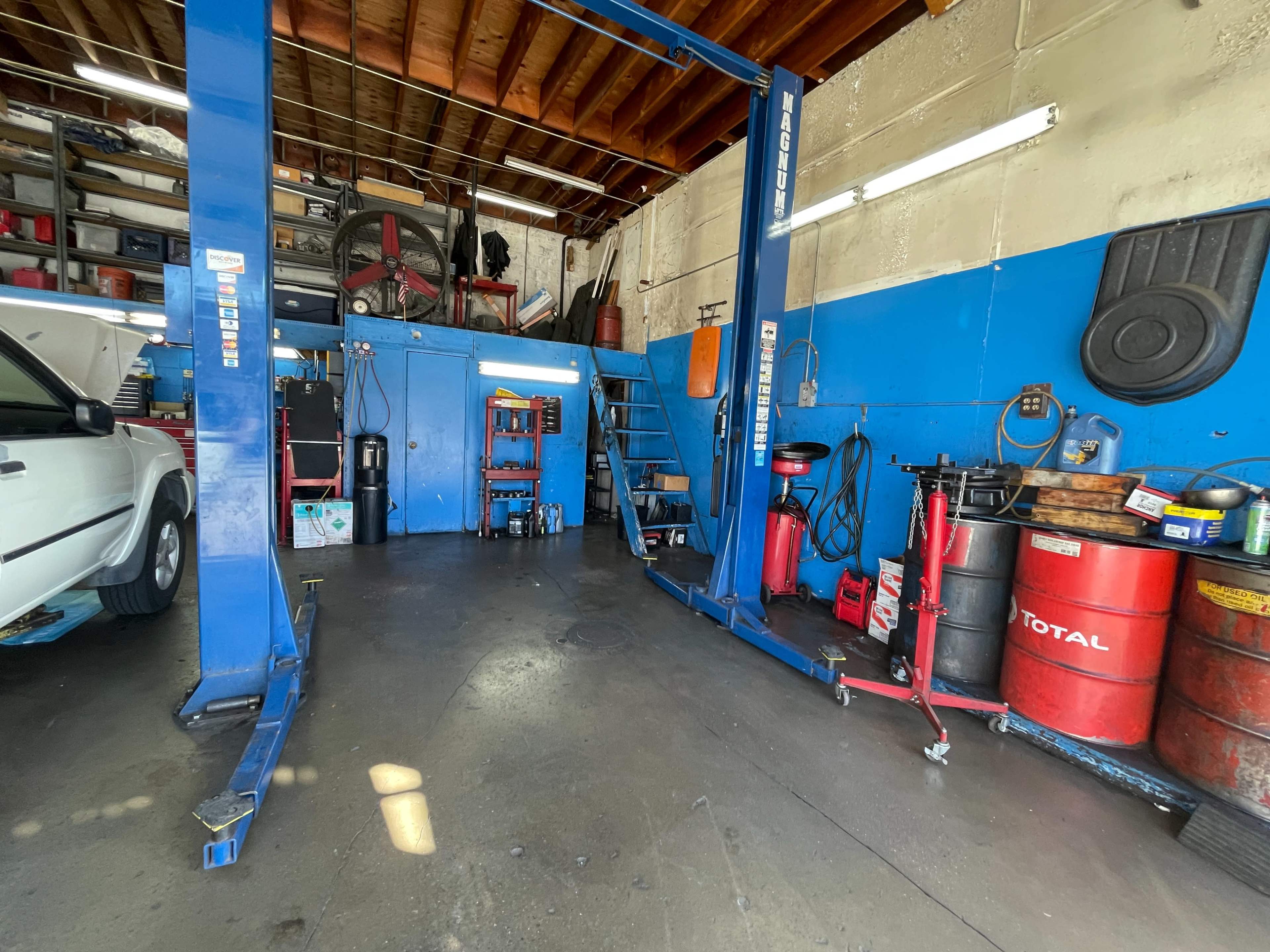 An auto repair shop interior featuring a car lift, tool storage, and various equipment on the floor.