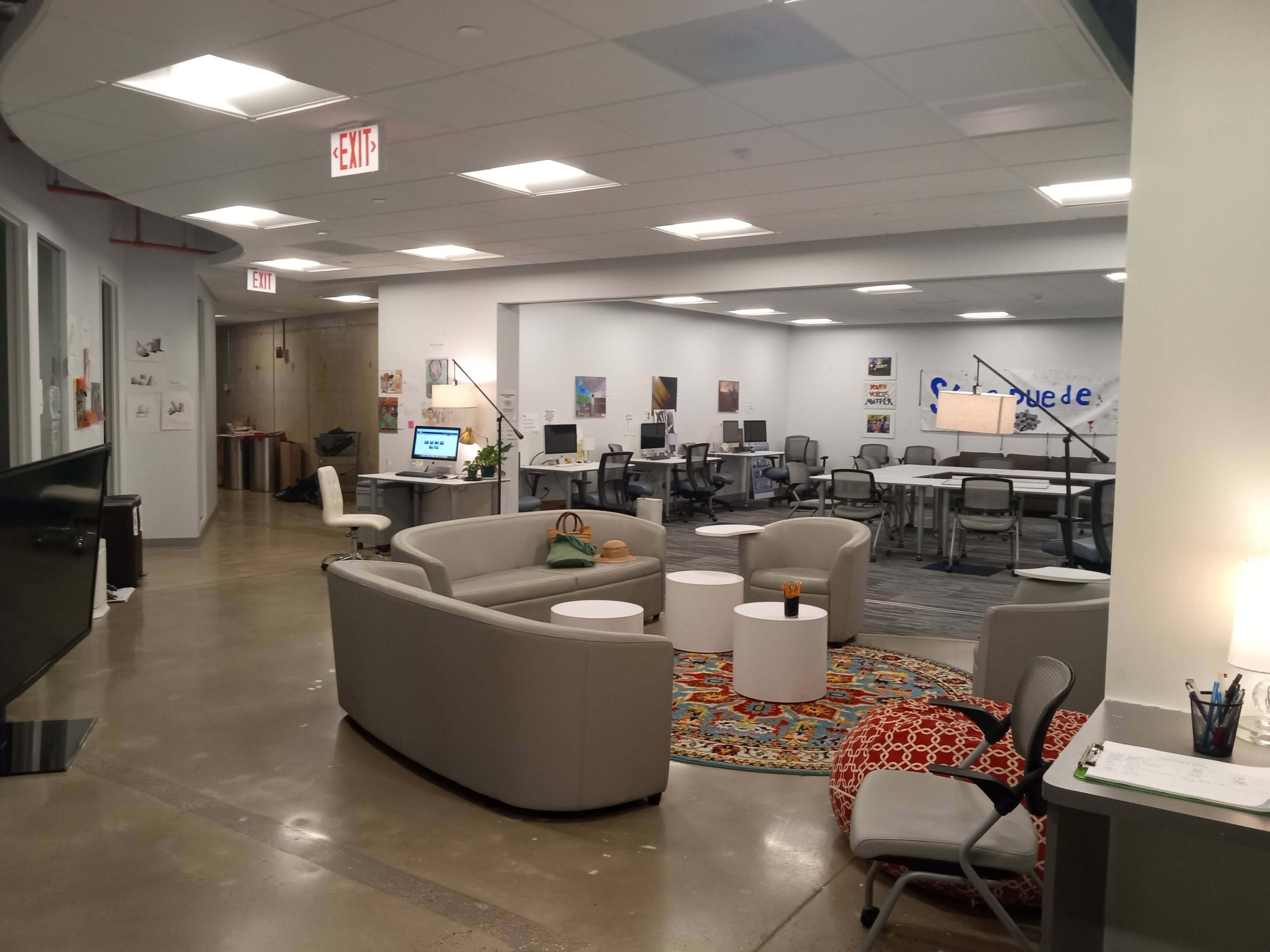 A modern, open office space with seating areas, workstations, and decorative artwork on the walls.