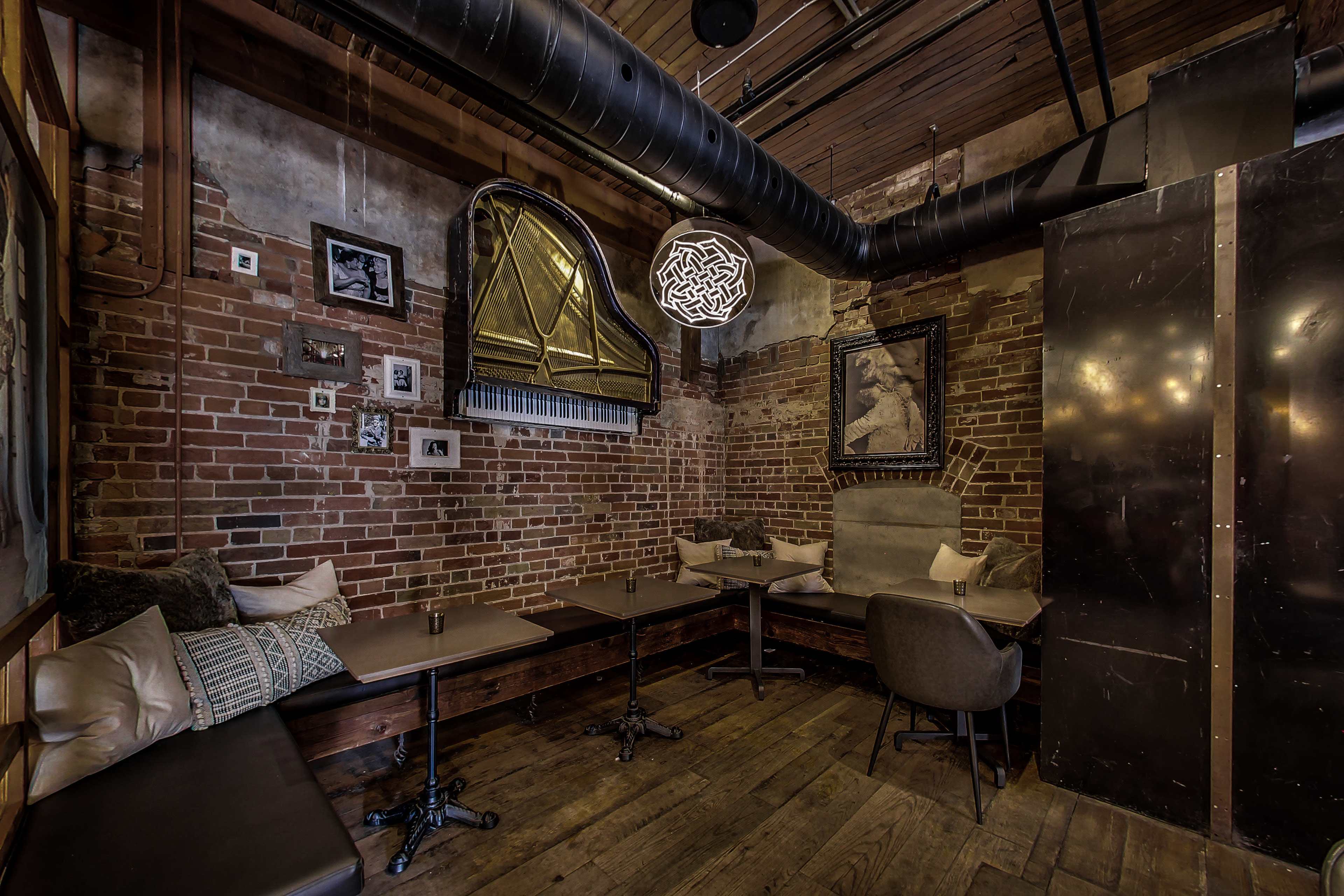 The image shows a cozy restaurant interior with exposed brick walls, wooden tables, and stylish lighting fixtures.