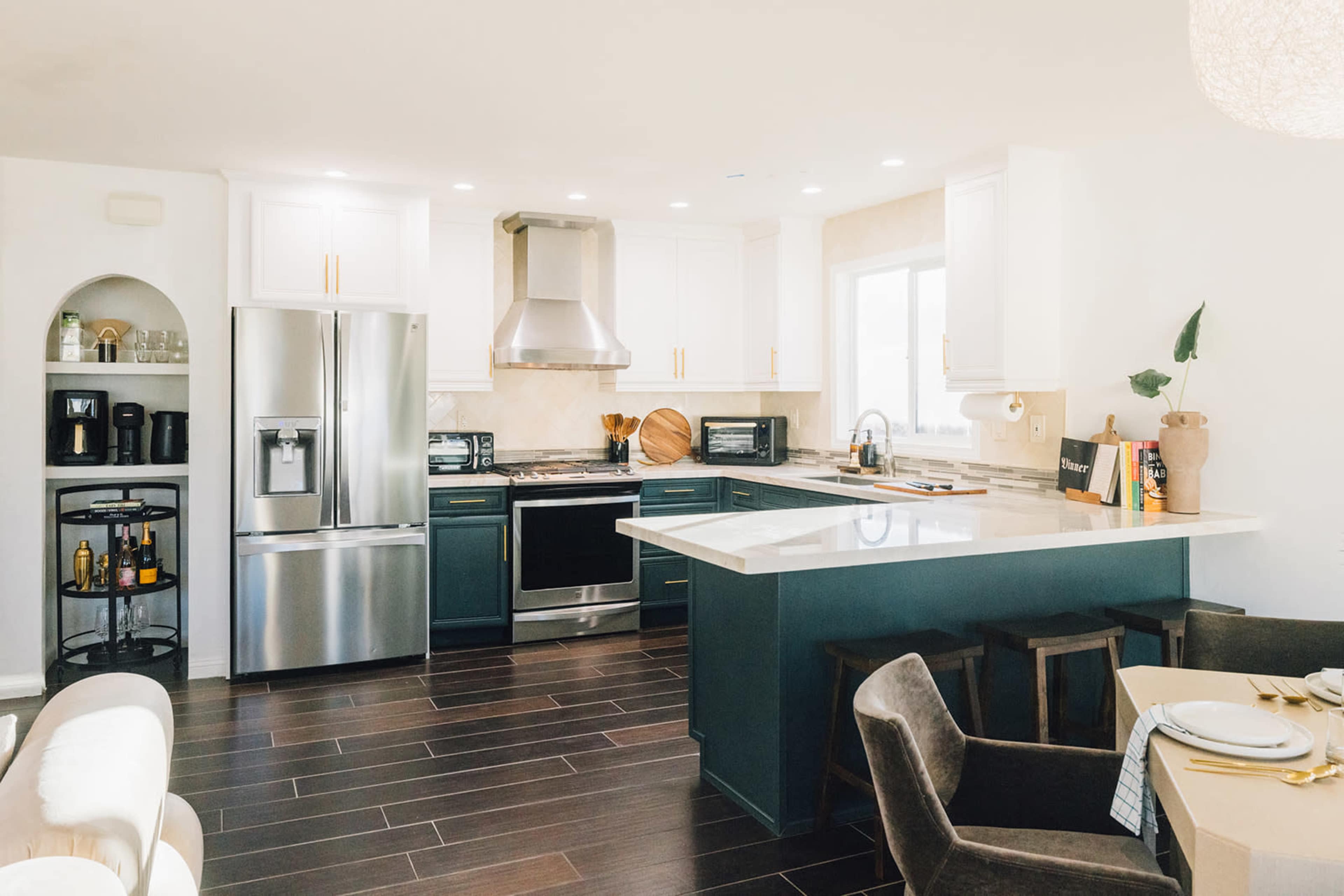 The kitchen features modern appliances, a large island with seating, and a mix of dark and light cabinetry.