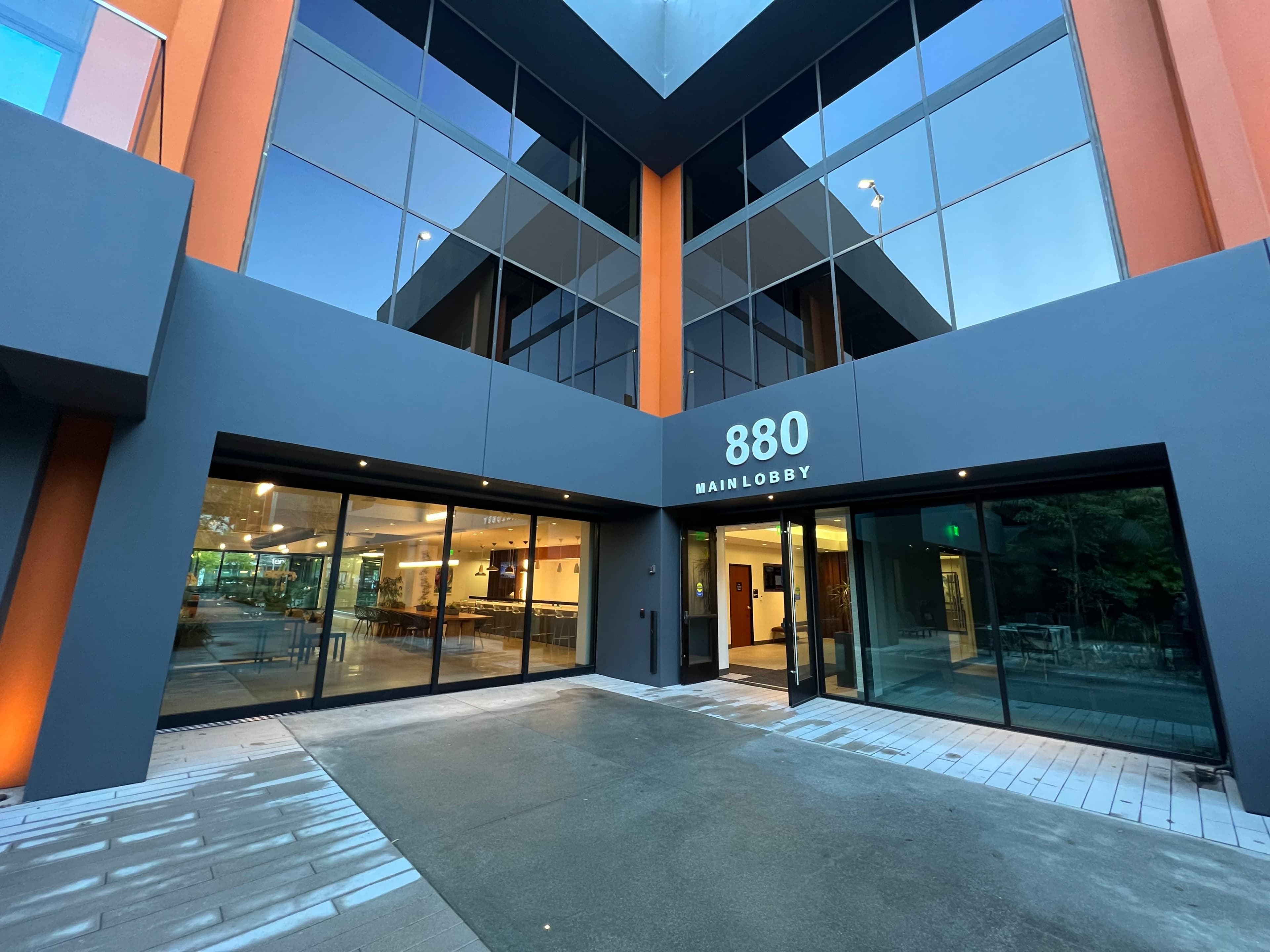 The image shows a modern building entrance with large glass doors and the number "880" prominently displayed above the entryway.