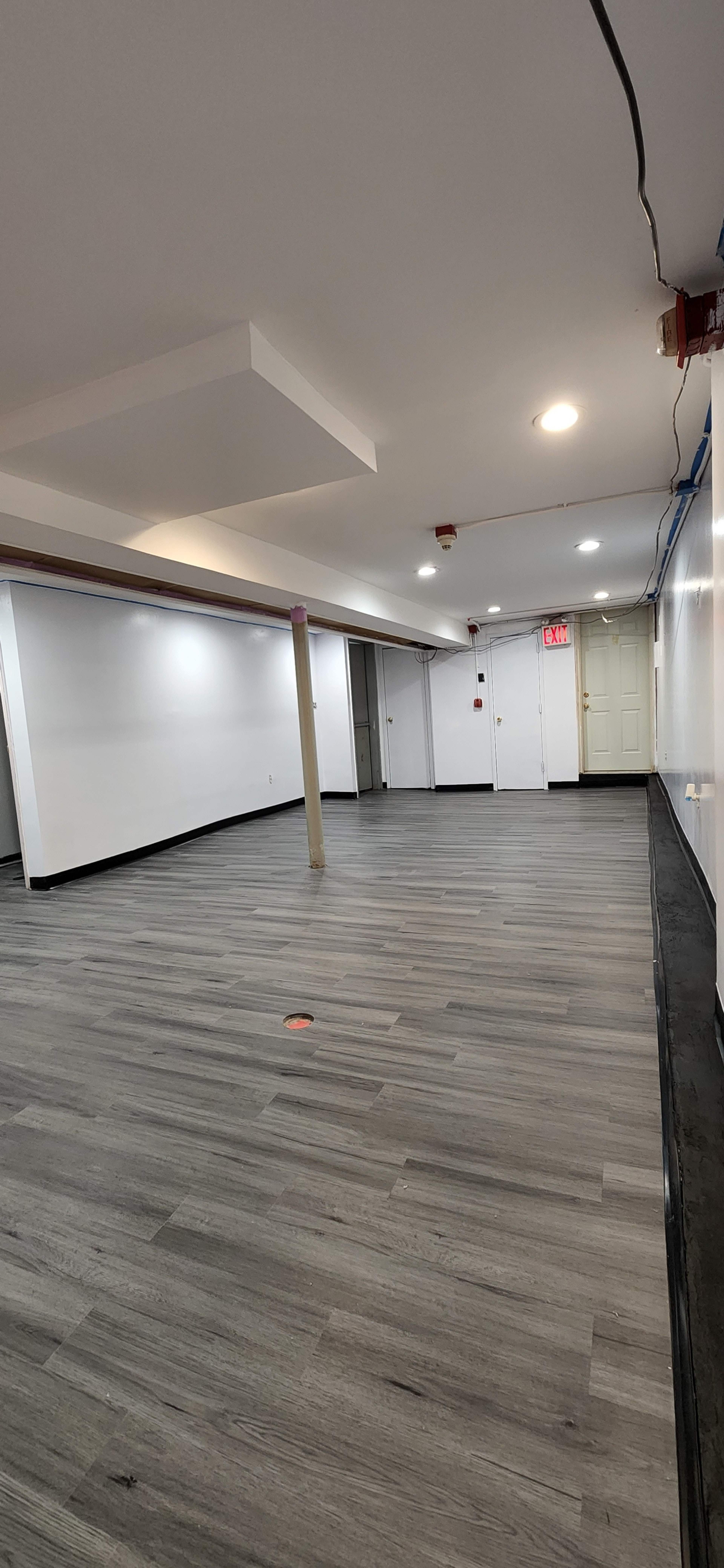 An empty room with a gray wooden floor, white walls, and a column in the center.