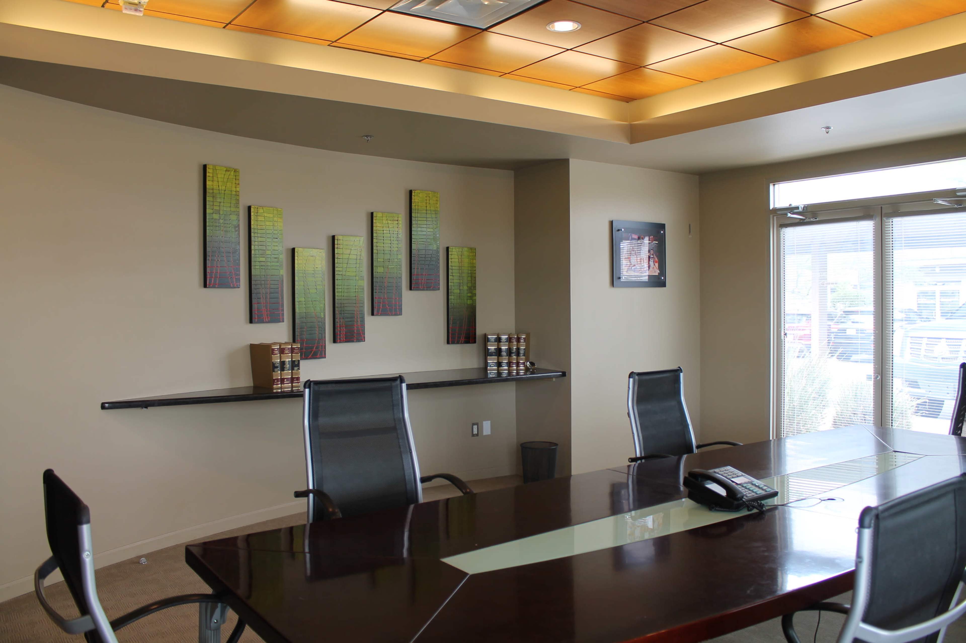 A modern conference room with a long table, several chairs, and artwork displayed on the walls.