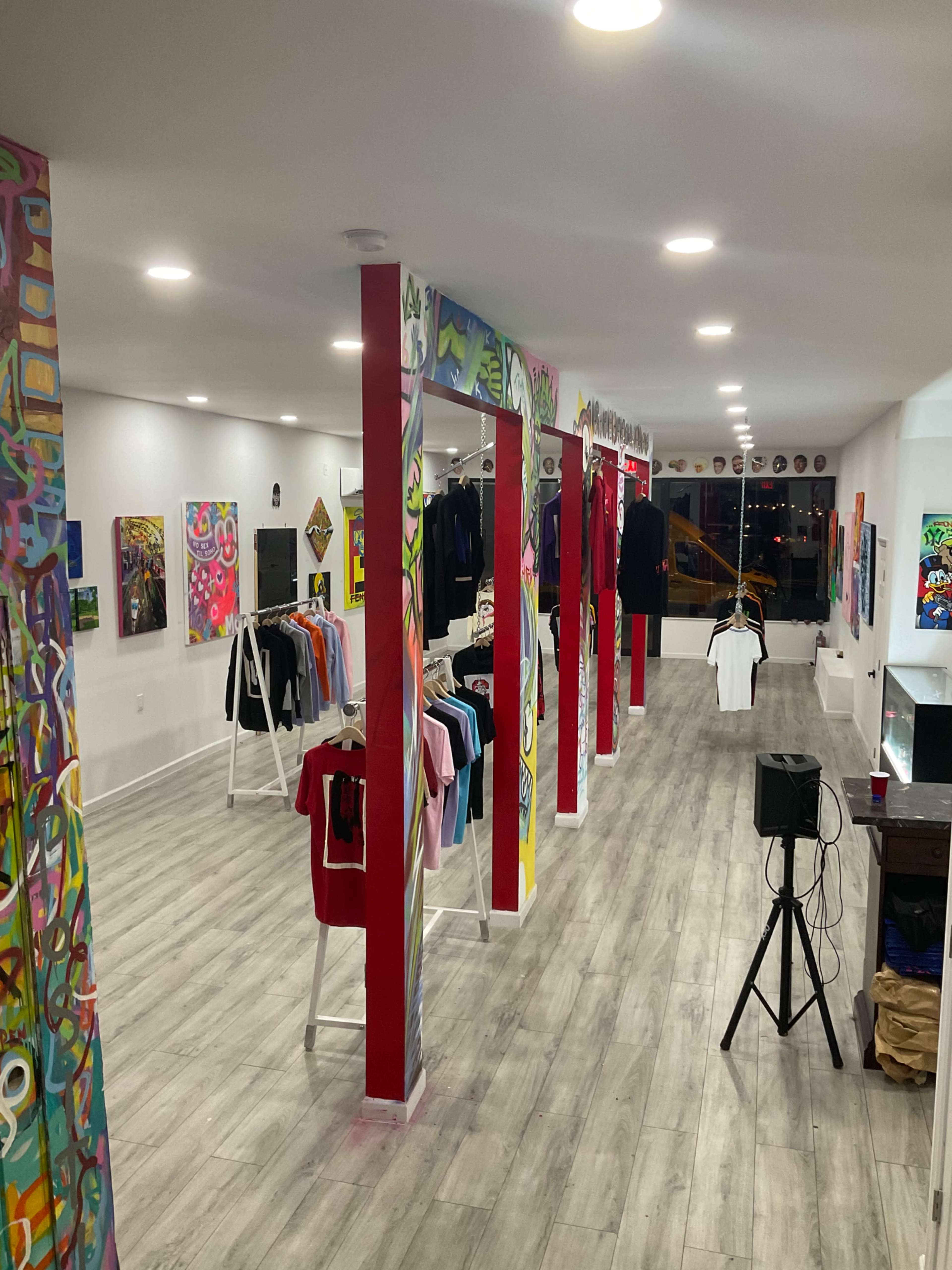 A clothing store featuring vibrant graffiti on the pillars and a display of various shirts arranged on racks.