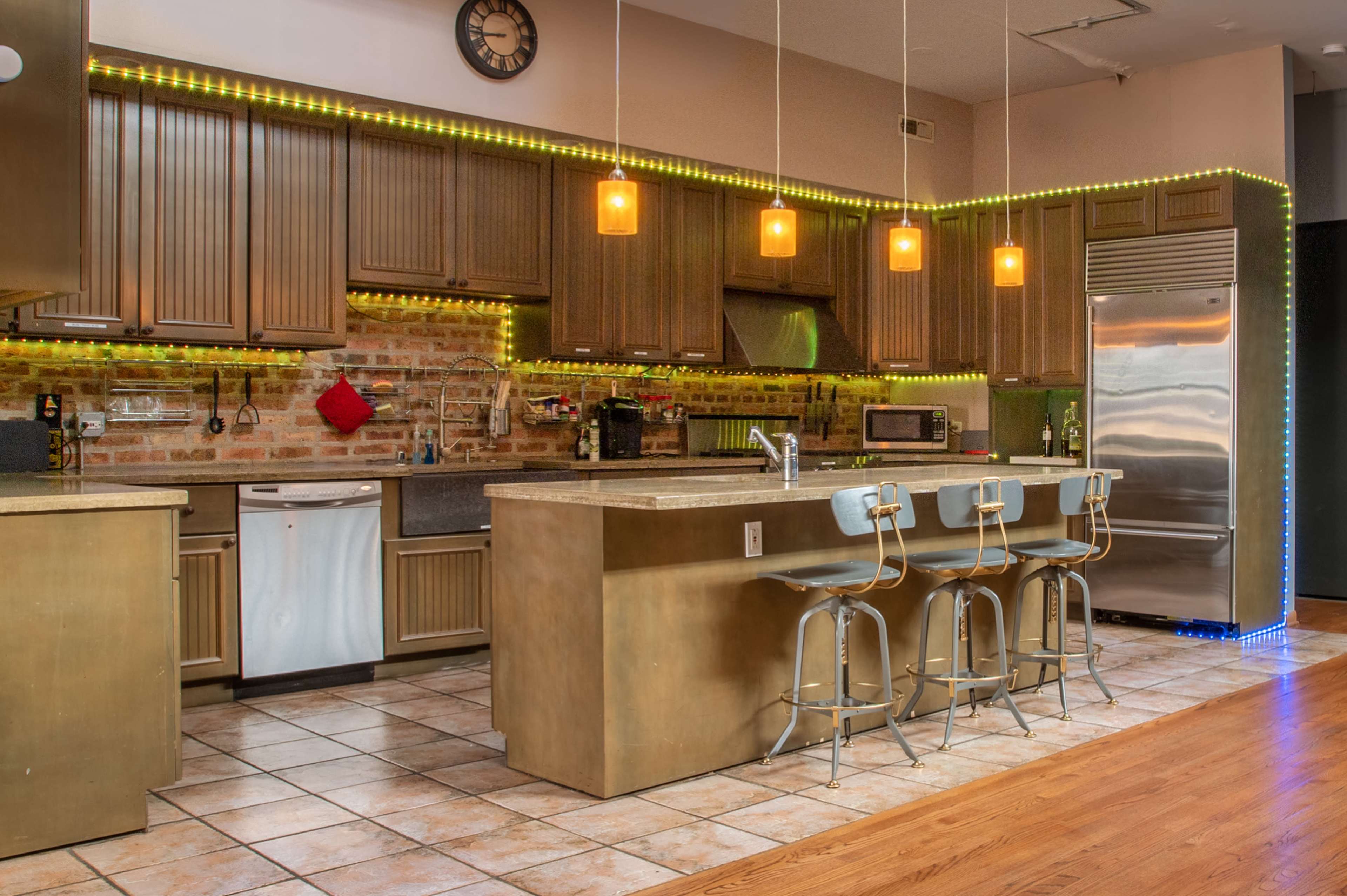 A modern kitchen with dark cabinetry, a large island with bar stools, and warm pendant lighting illuminating the space.