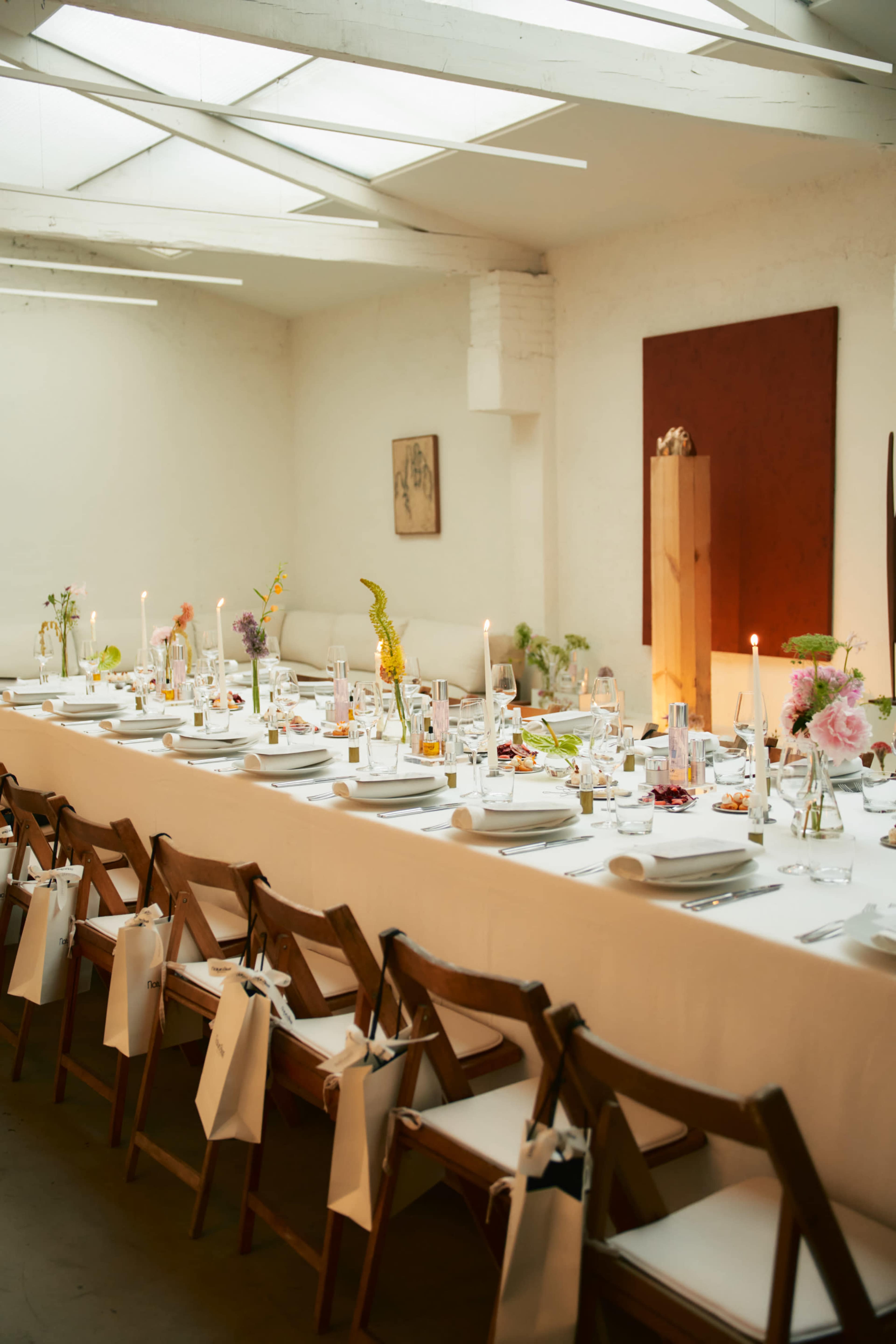 A long dining table is set with plates, glasses, and floral arrangements, surrounded by wooden chairs.