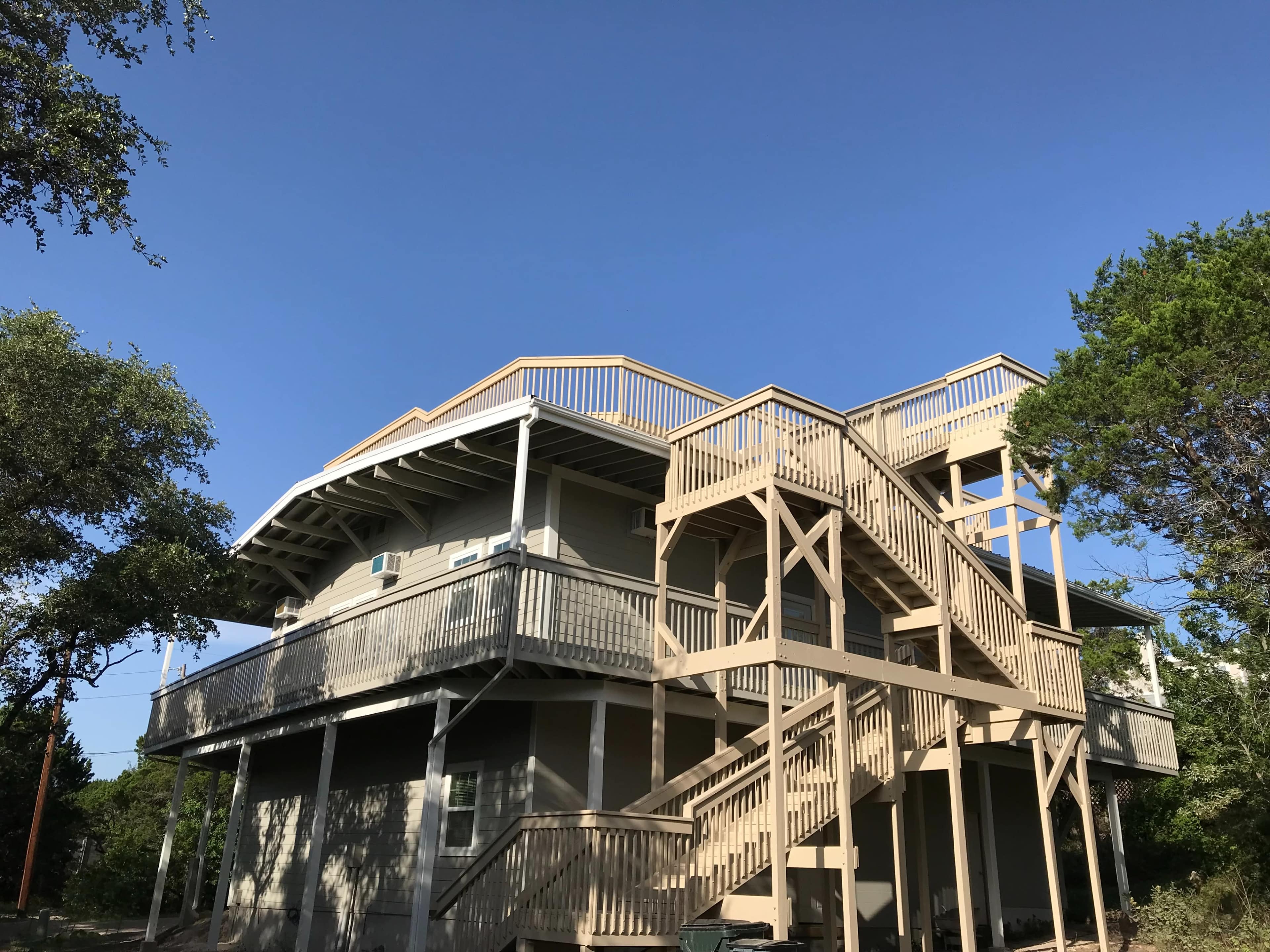 The image shows a multi-story wooden house with multiple balconies and an external staircase.
