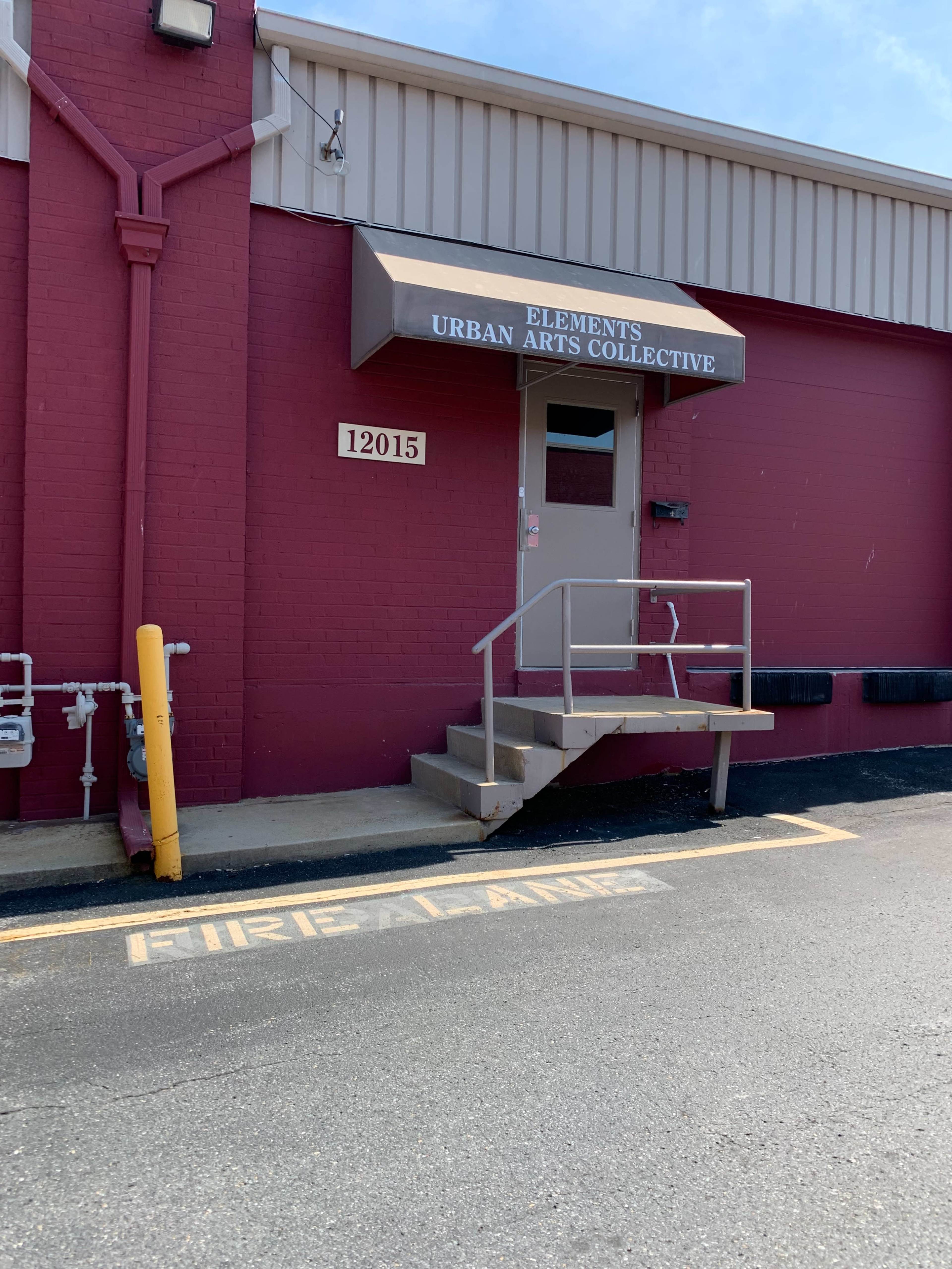 The entrance of a building labeled "Elements Urban Arts Collective," with a fire lane marked in front.