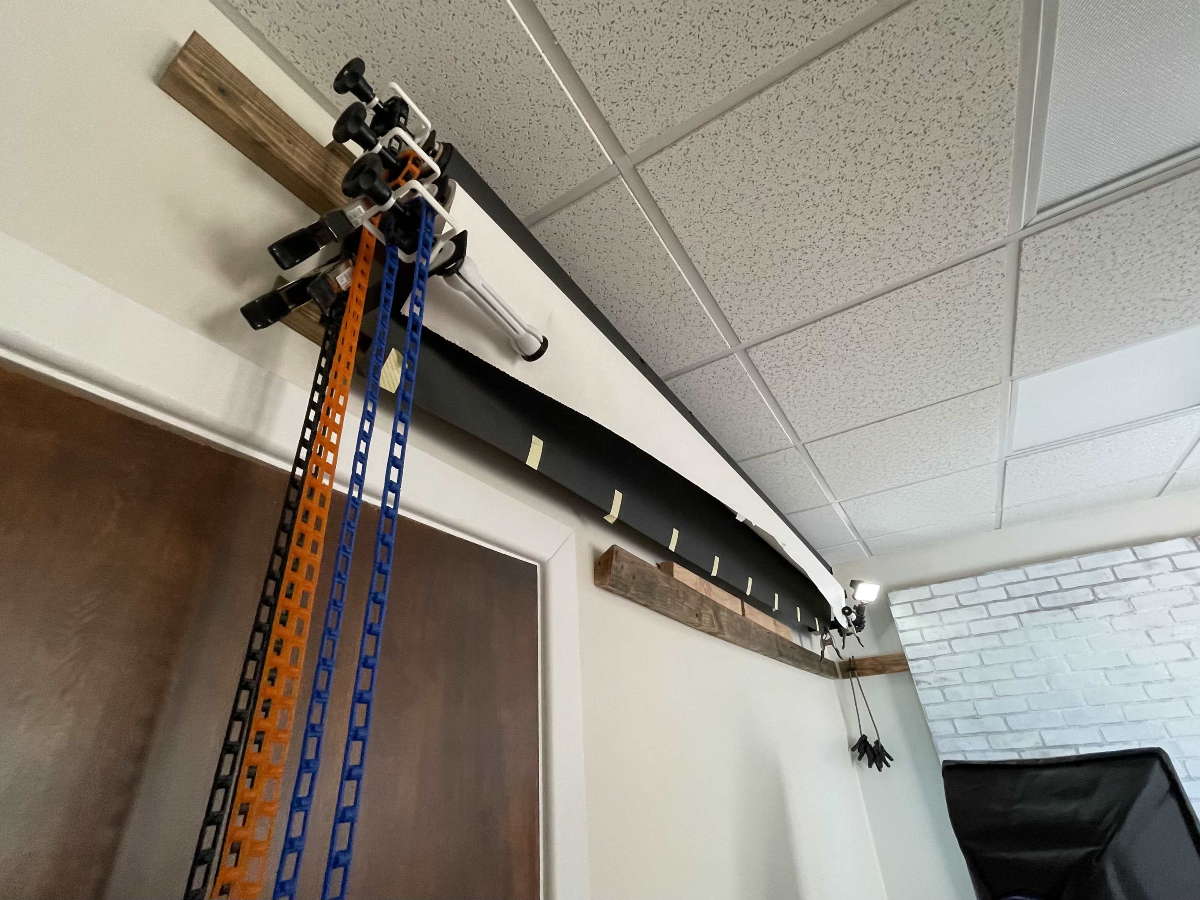 A set of equipment mounted on a wall, including a curved track, a camera setup, and measurement strips arranged along the ceiling.