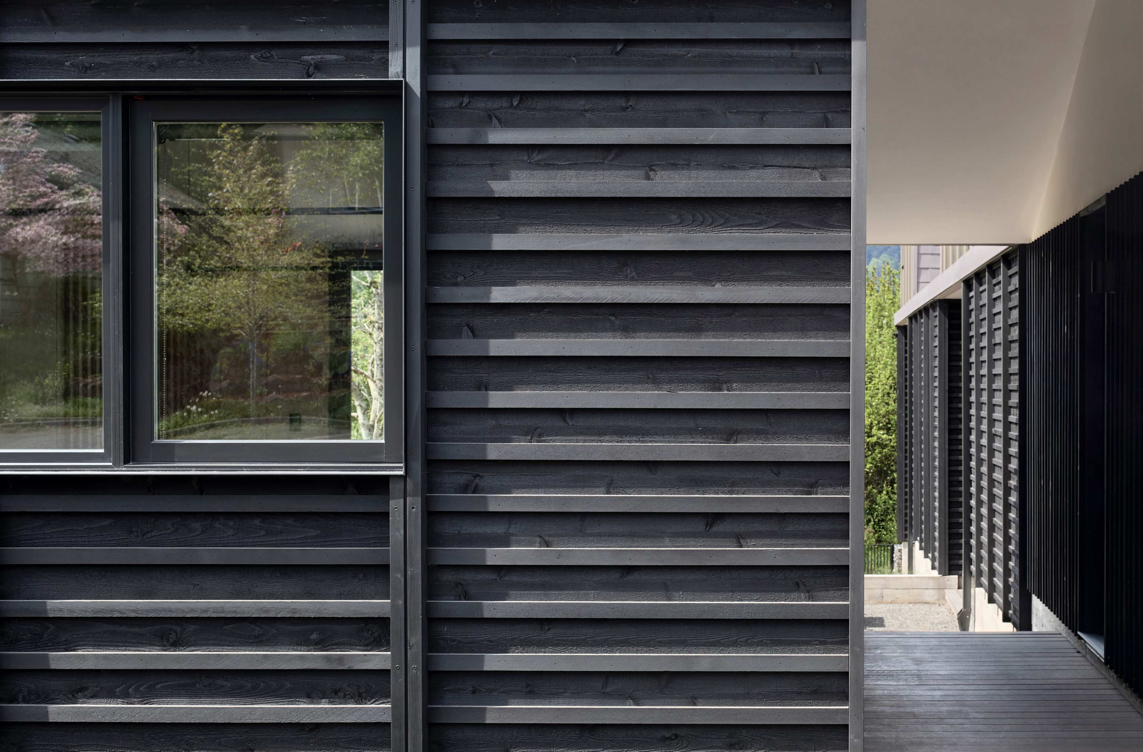 A modern building facade with dark wood paneling and a prominent window.
