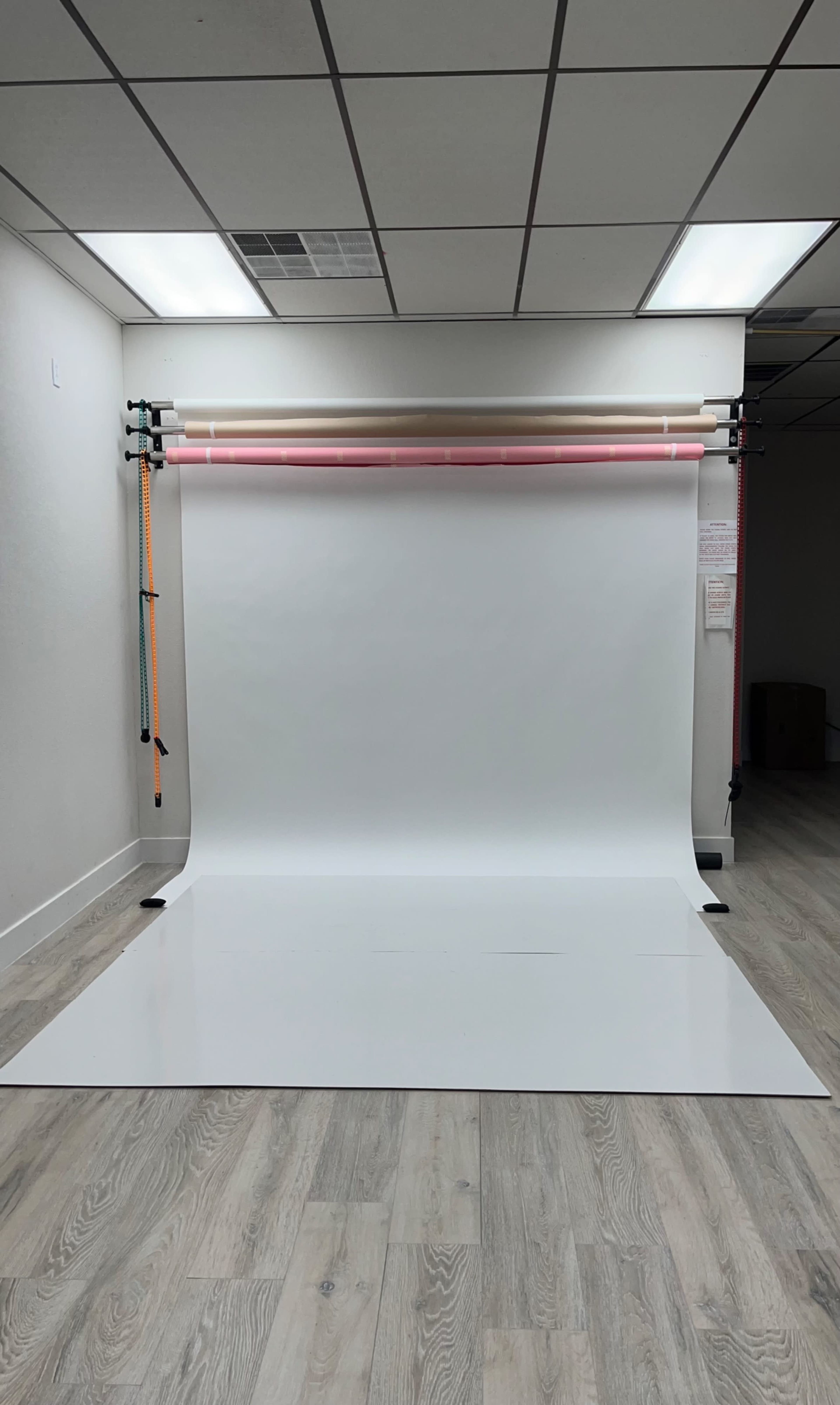 The image shows a photography studio with a white backdrop set up against a wall.