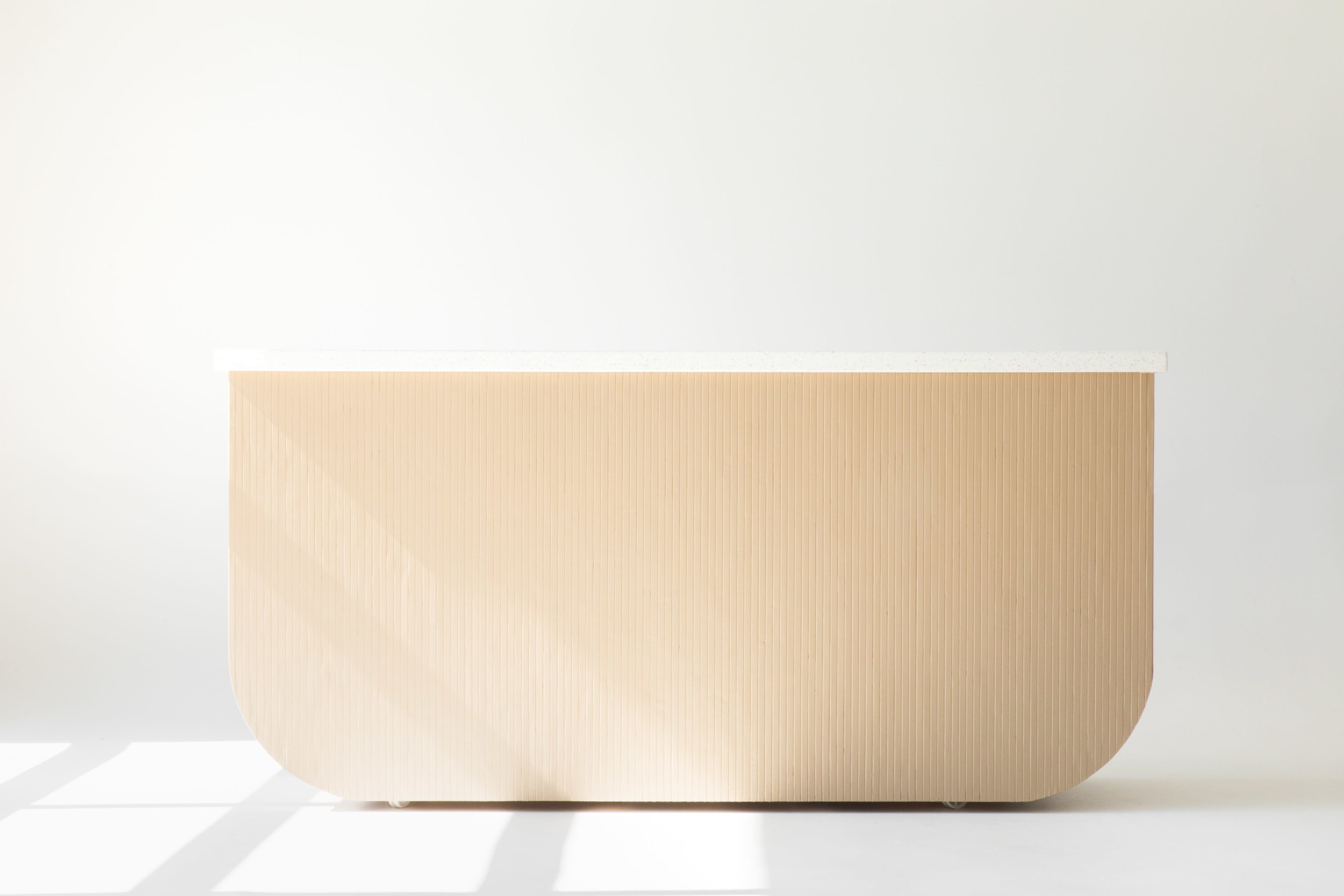 A beige, curved reception desk with a smooth white countertop is positioned against a plain white background.