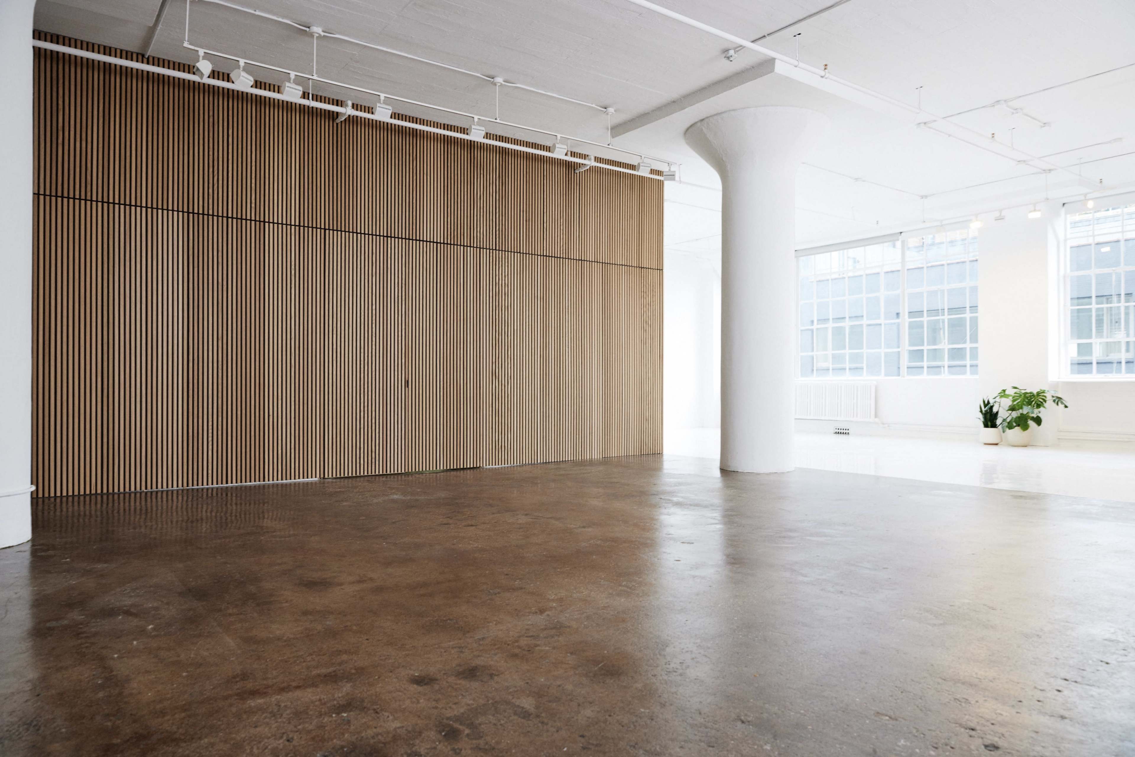 A spacious, minimalist interior featuring a wooden wall with vertical slats and a concrete floor.