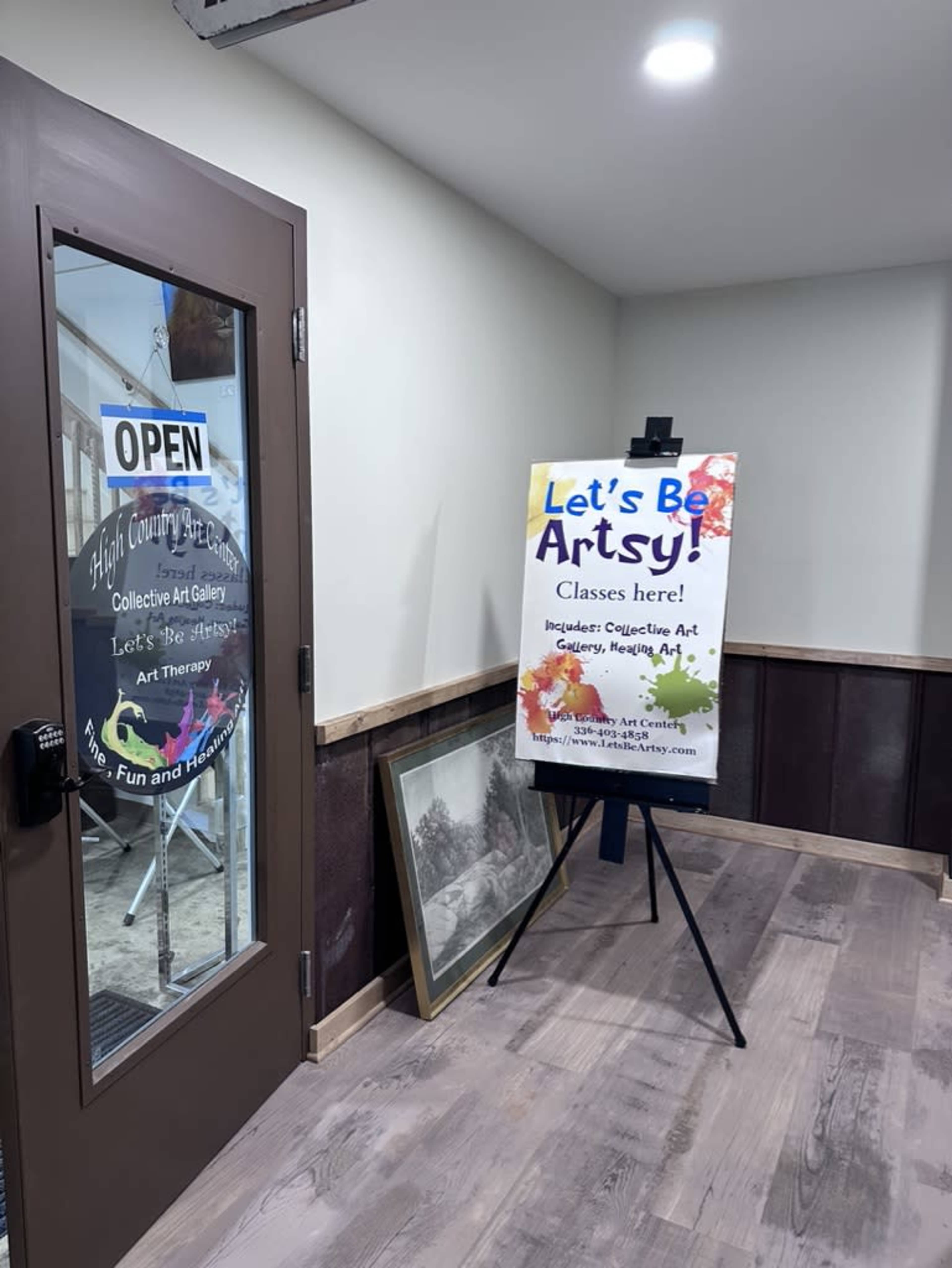 The image shows the entrance to an art studio with an open door, featuring a sign that promotes classes for creative activities.