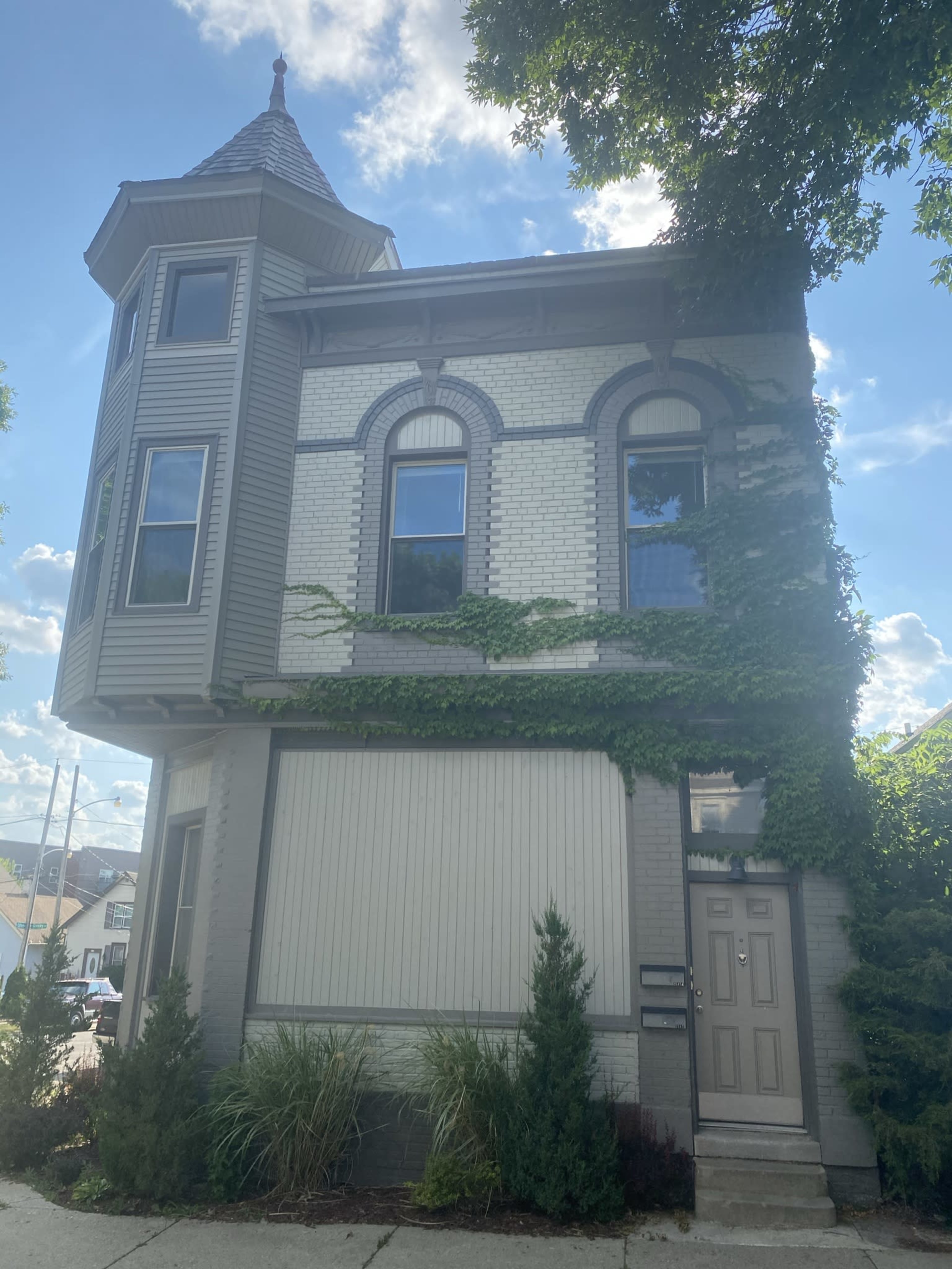 A three-story, brick building with architectural detailing and ivy growth covers part of its exterior.