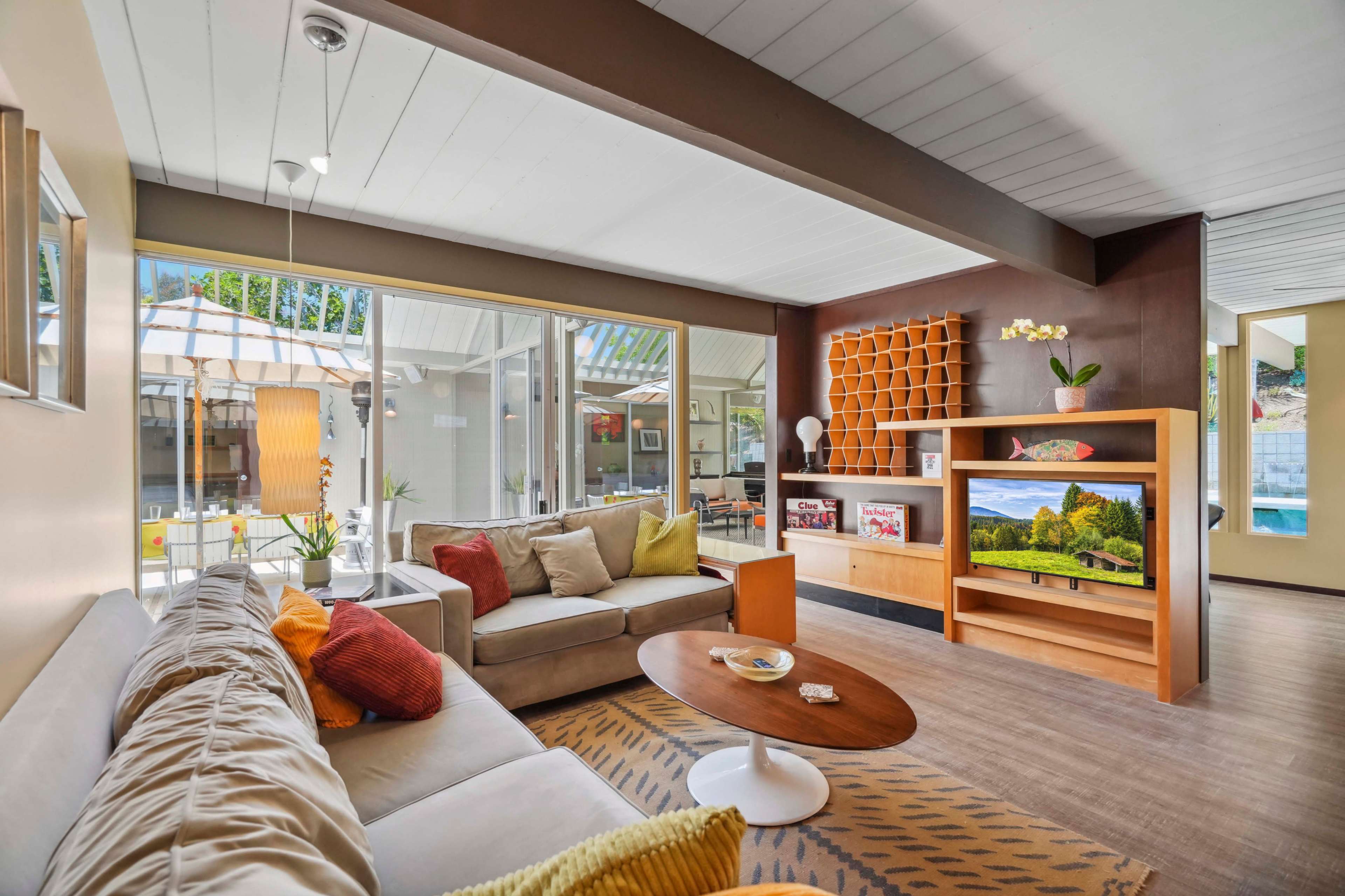 A modern living room featuring a beige couch, a round coffee table, and large windows allowing natural light to enter.