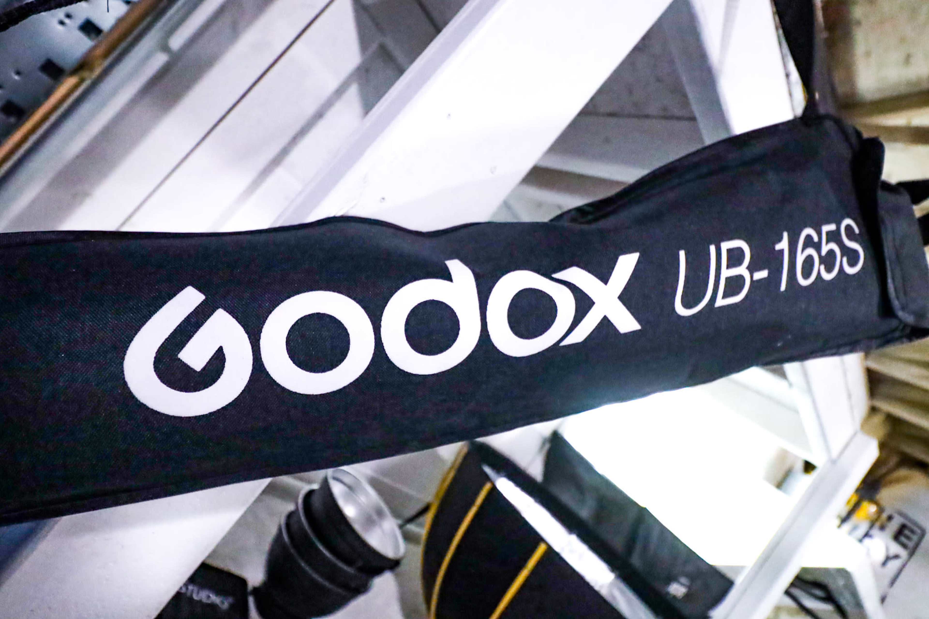 A close-up of a black carrying case labeled "Godox UB-16S" on a white shelf.