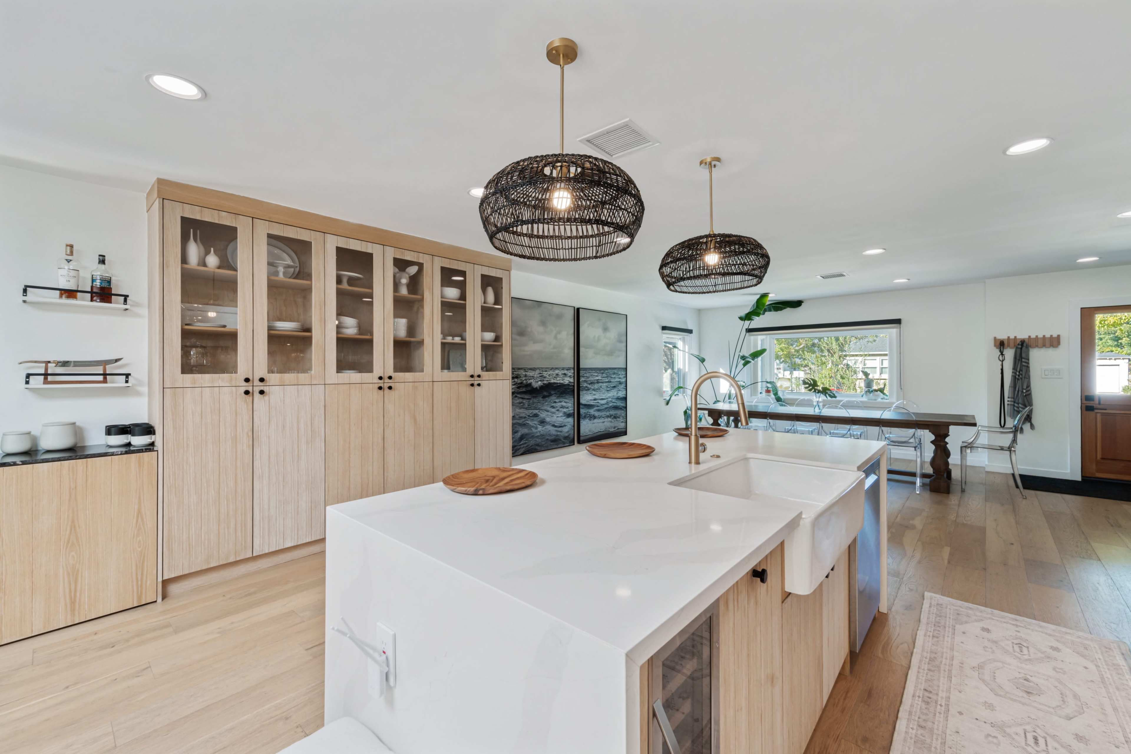 The image shows a modern kitchen with wooden cabinetry, a white countertop, and pendant lighting.