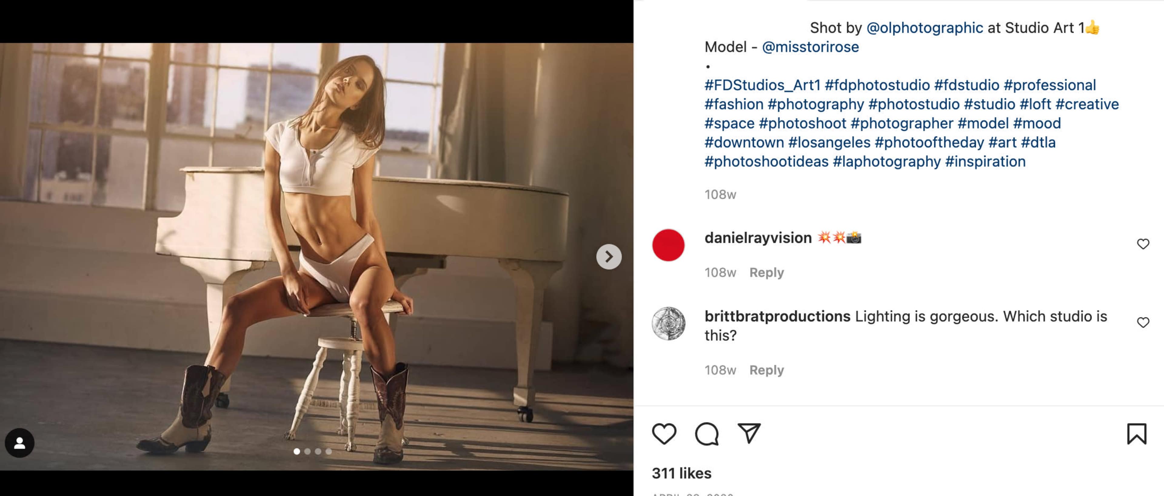 A model poses in a studio space, wearing a crop top and shorts, with cowboy boots, against a backdrop of soft lighting.