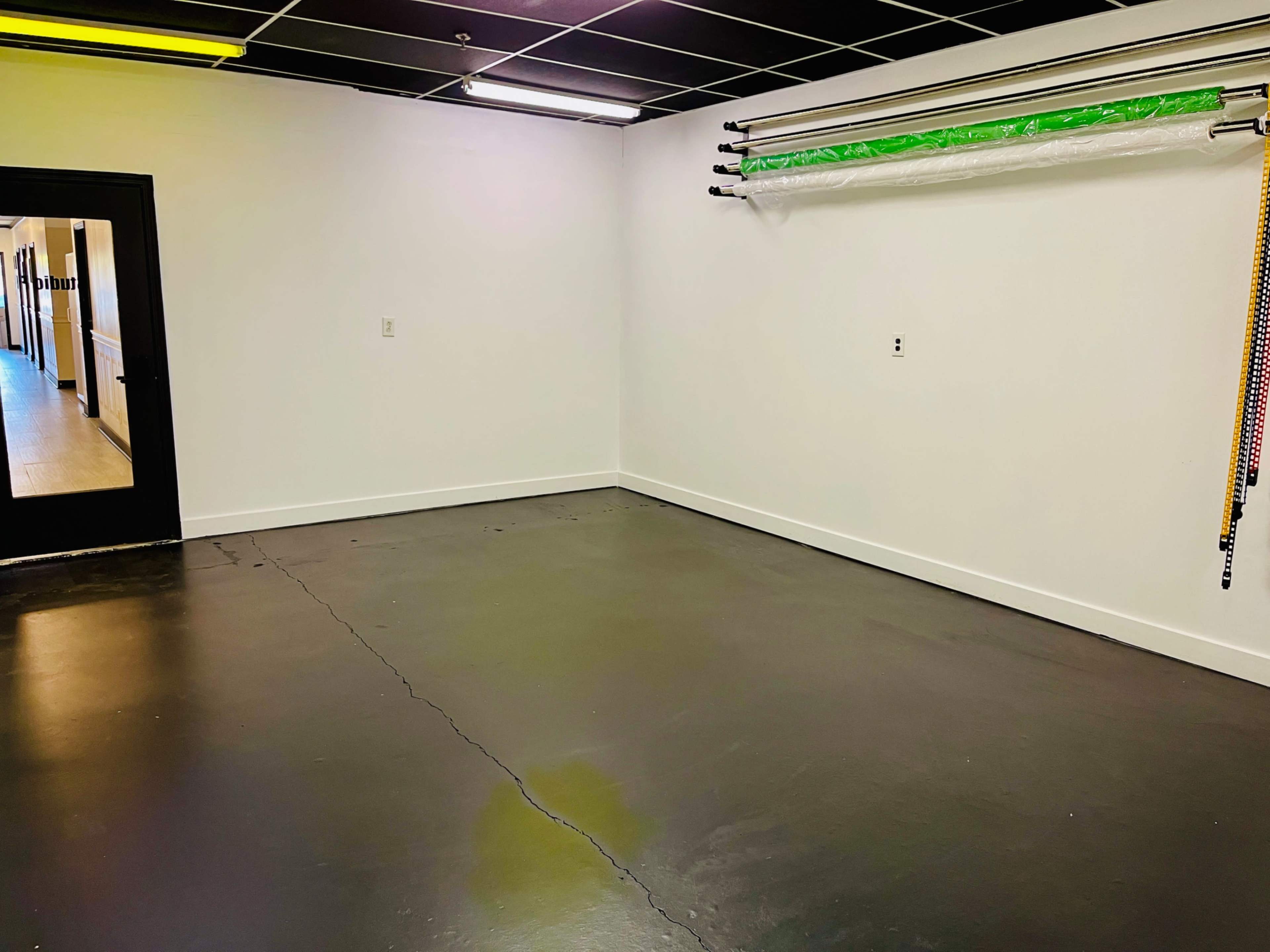 An empty room with a concrete floor, white walls, and a door leading to another space.
