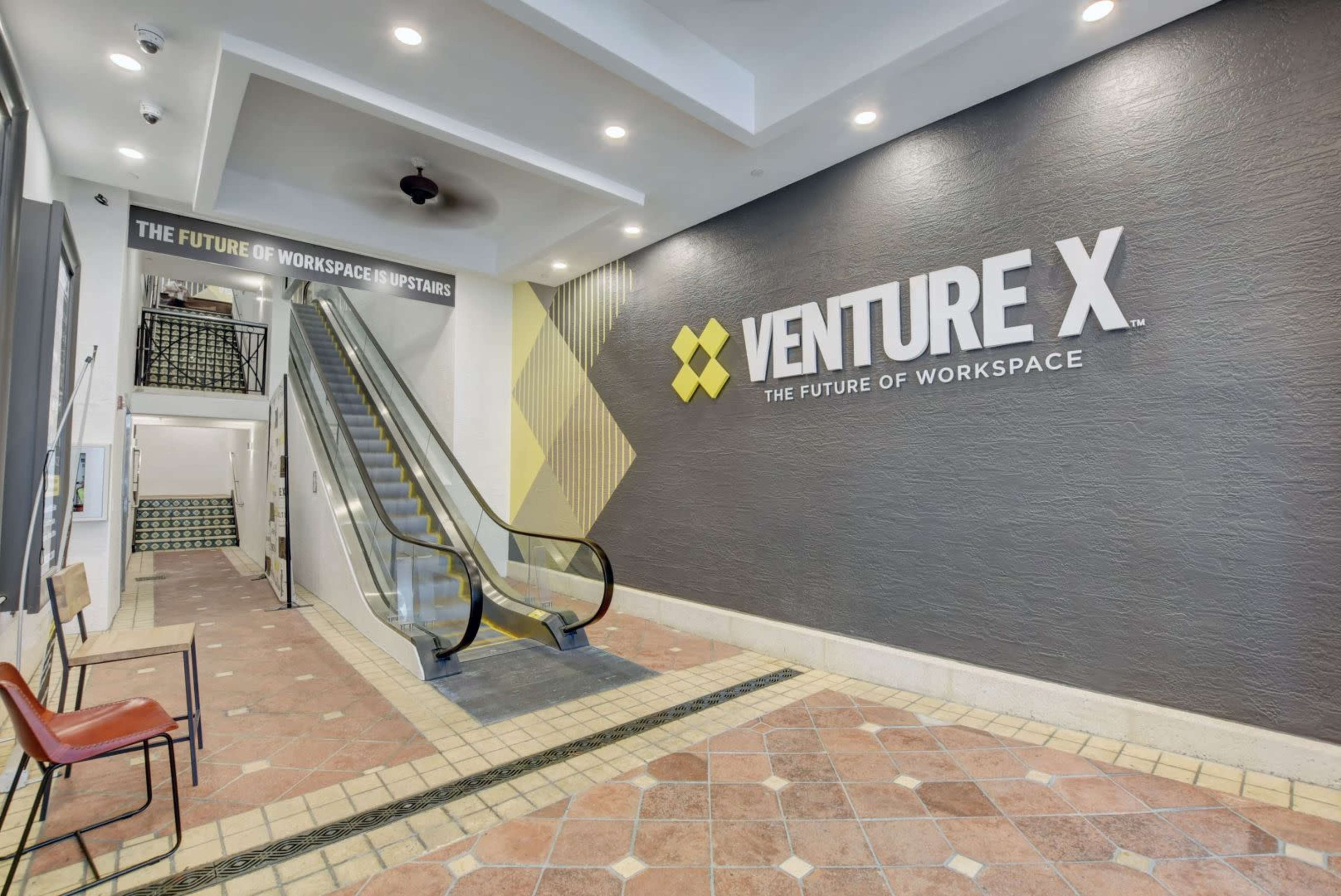 The image shows a stairway leading upward in a lobby area with a prominent sign for "Venture X" on the wall.