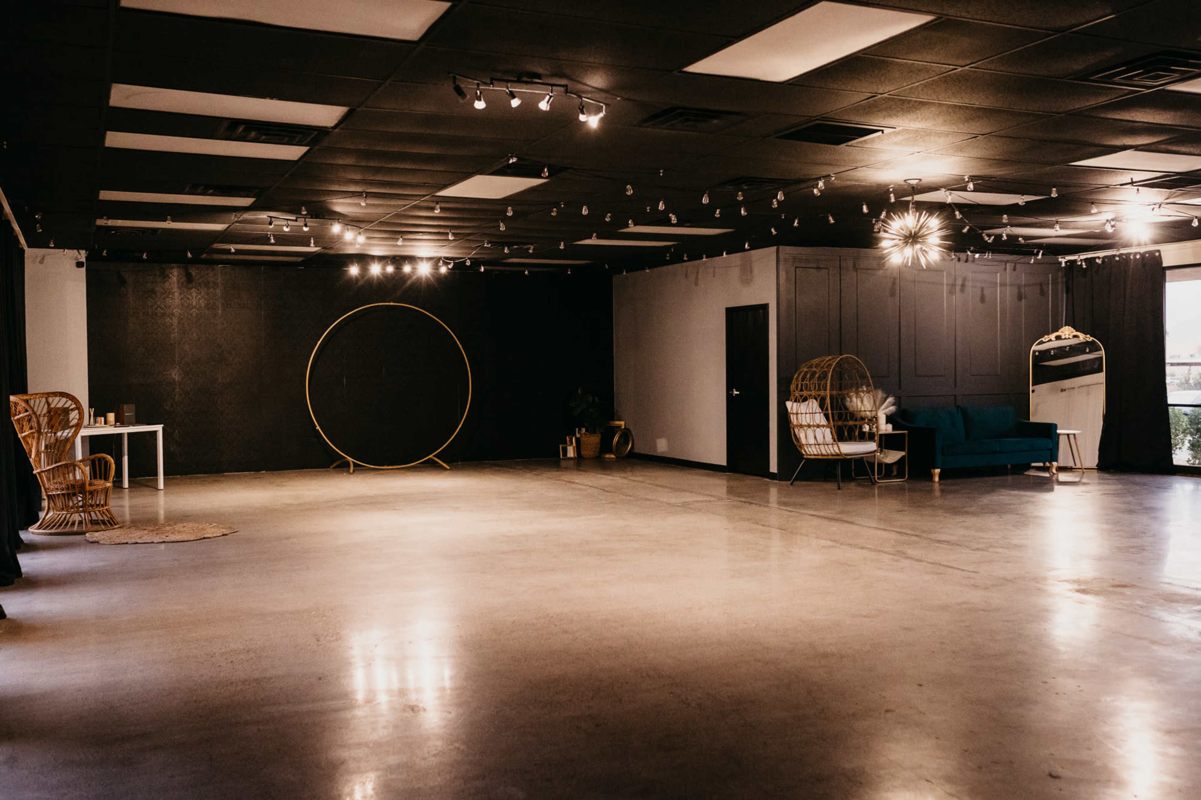 A spacious, empty room with a circular backdrop, a blue couch, a white table, and a few decorative elements.