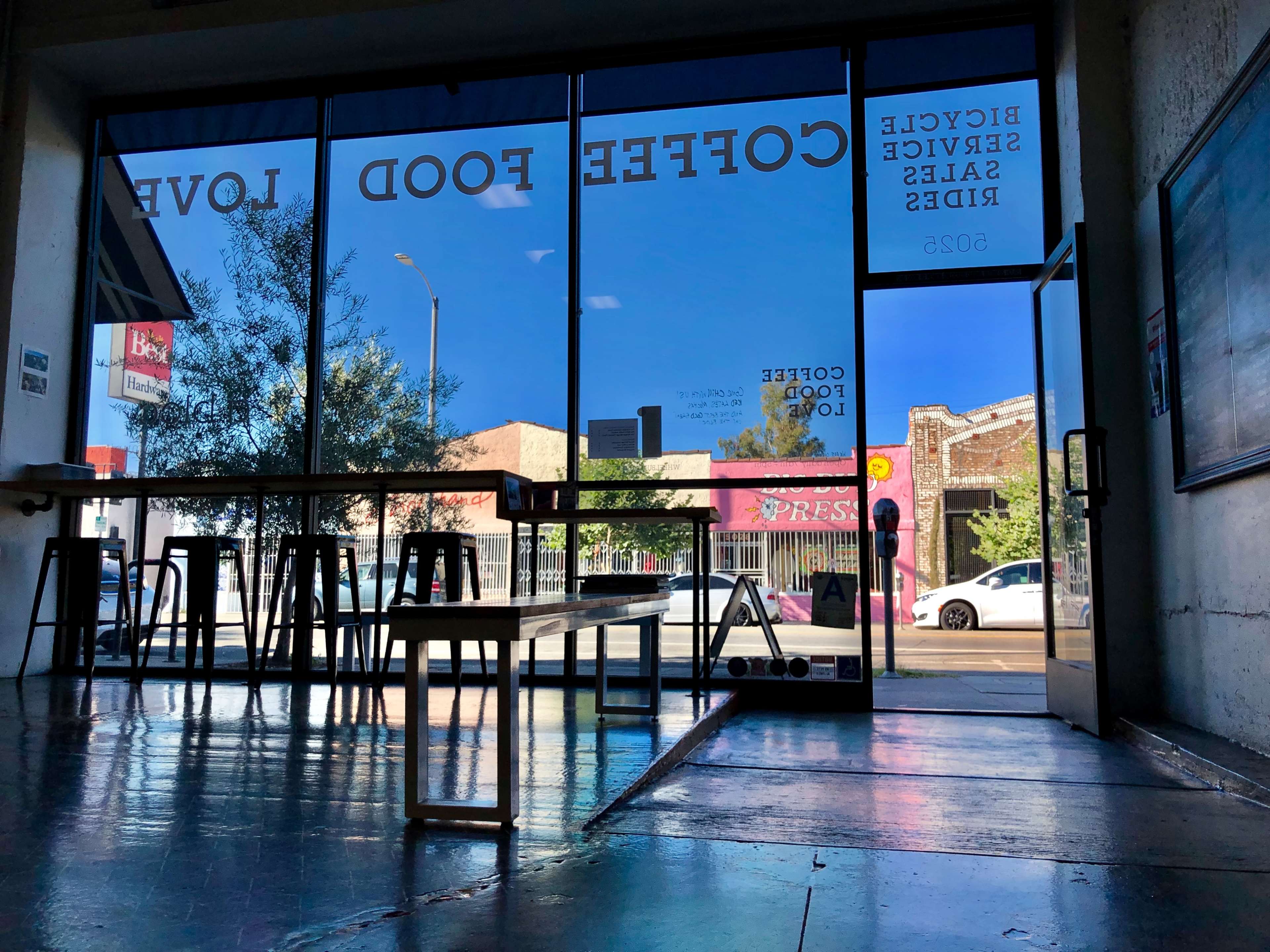 A café interior with large windows displaying a street scene and signage on the glass indicating "Coffee Food Love."