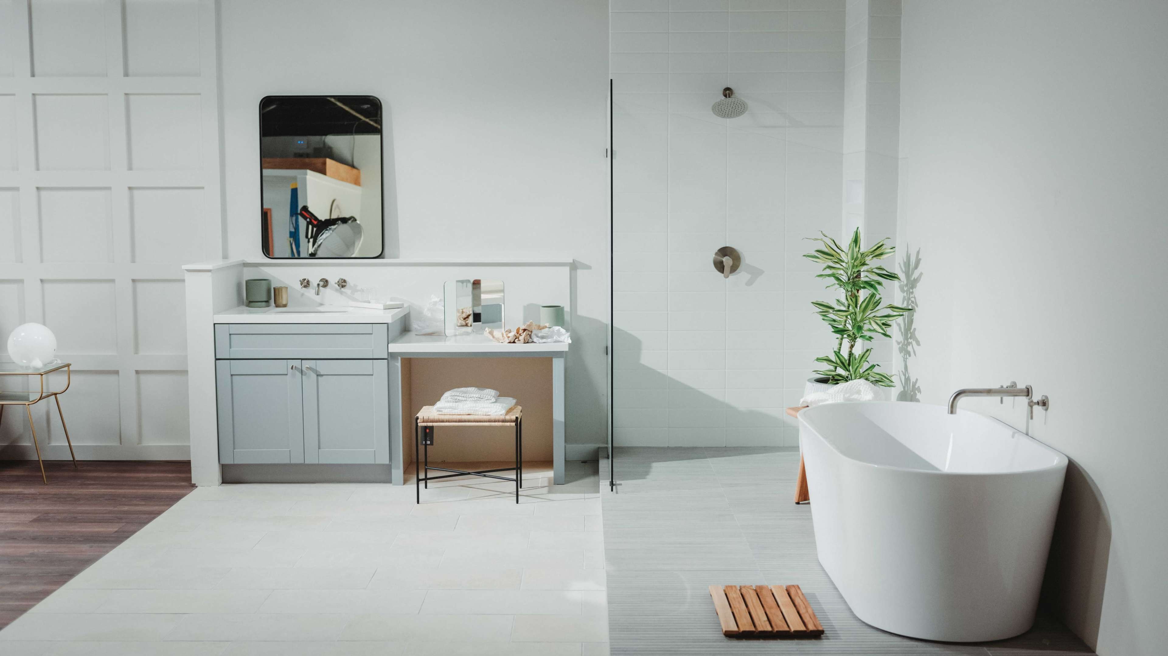 A modern bathroom featuring a freestanding bathtub, a walk-in shower, a large mirror, a vanity with sink, and potted plants.
