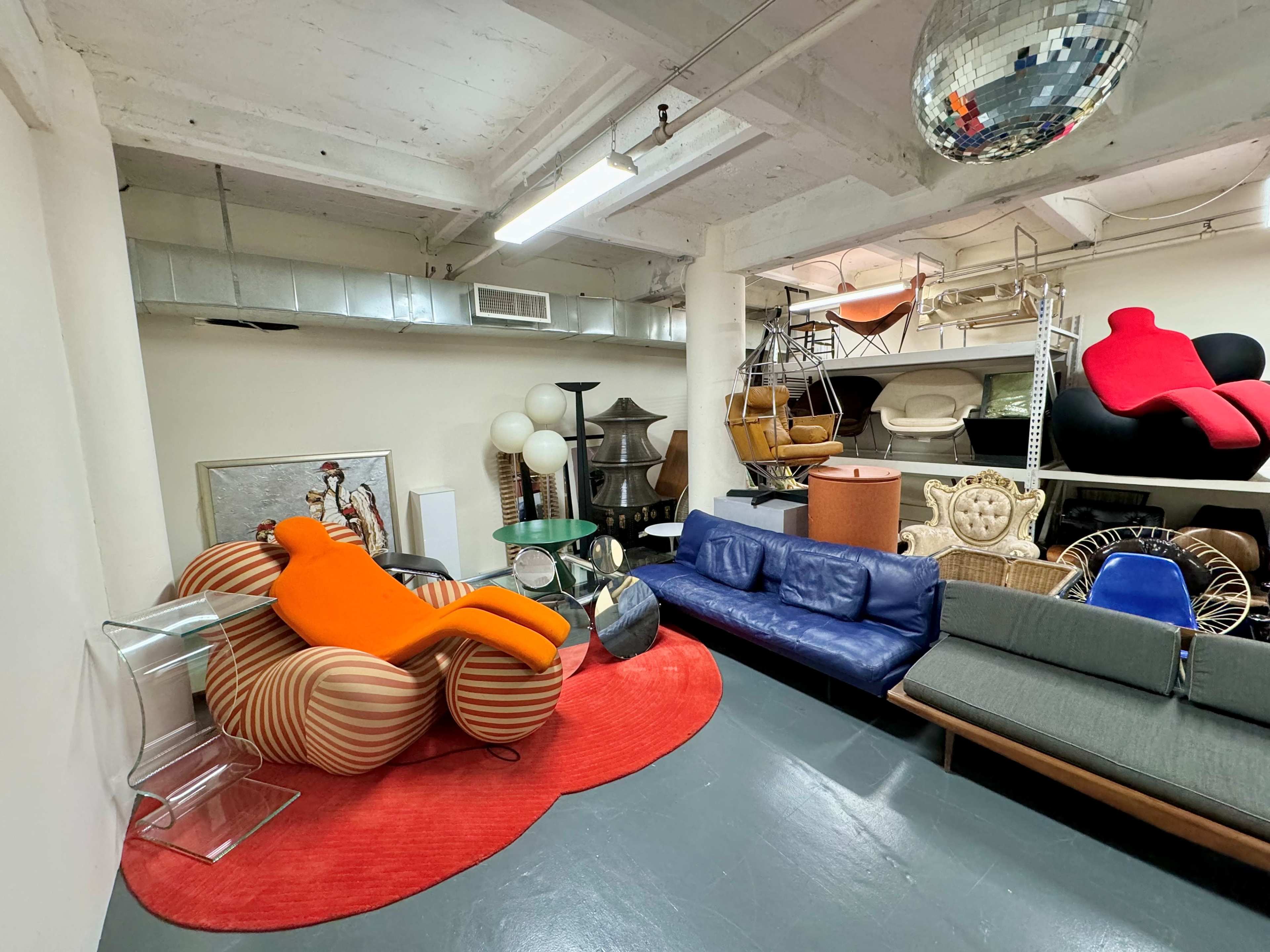 A spacious interior filled with various styles of furniture, including colorful chairs, a red rug, and decorative items.