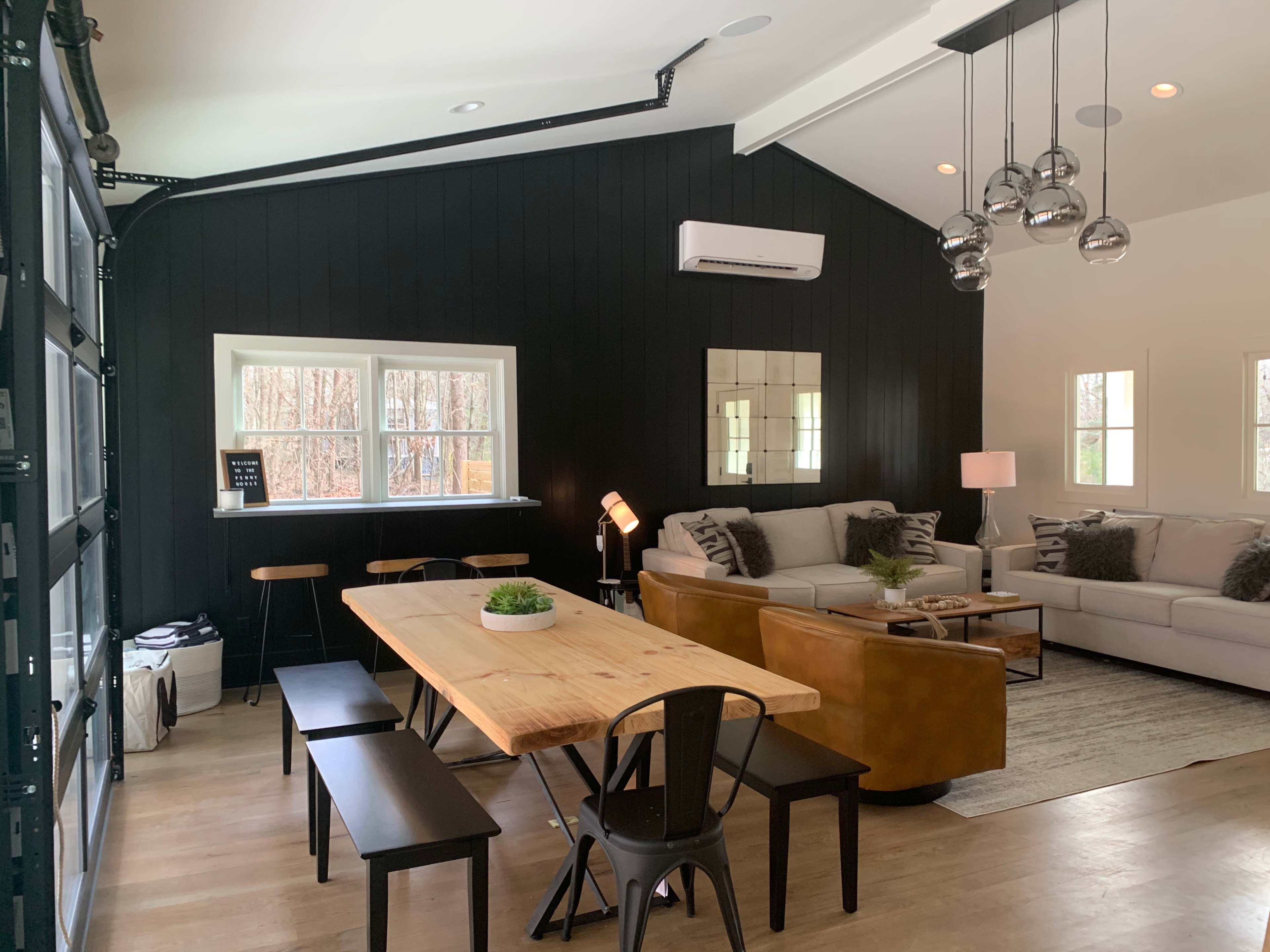 A modern living space featuring a dining table, seating area with a sofa, and large windows illuminating the room.