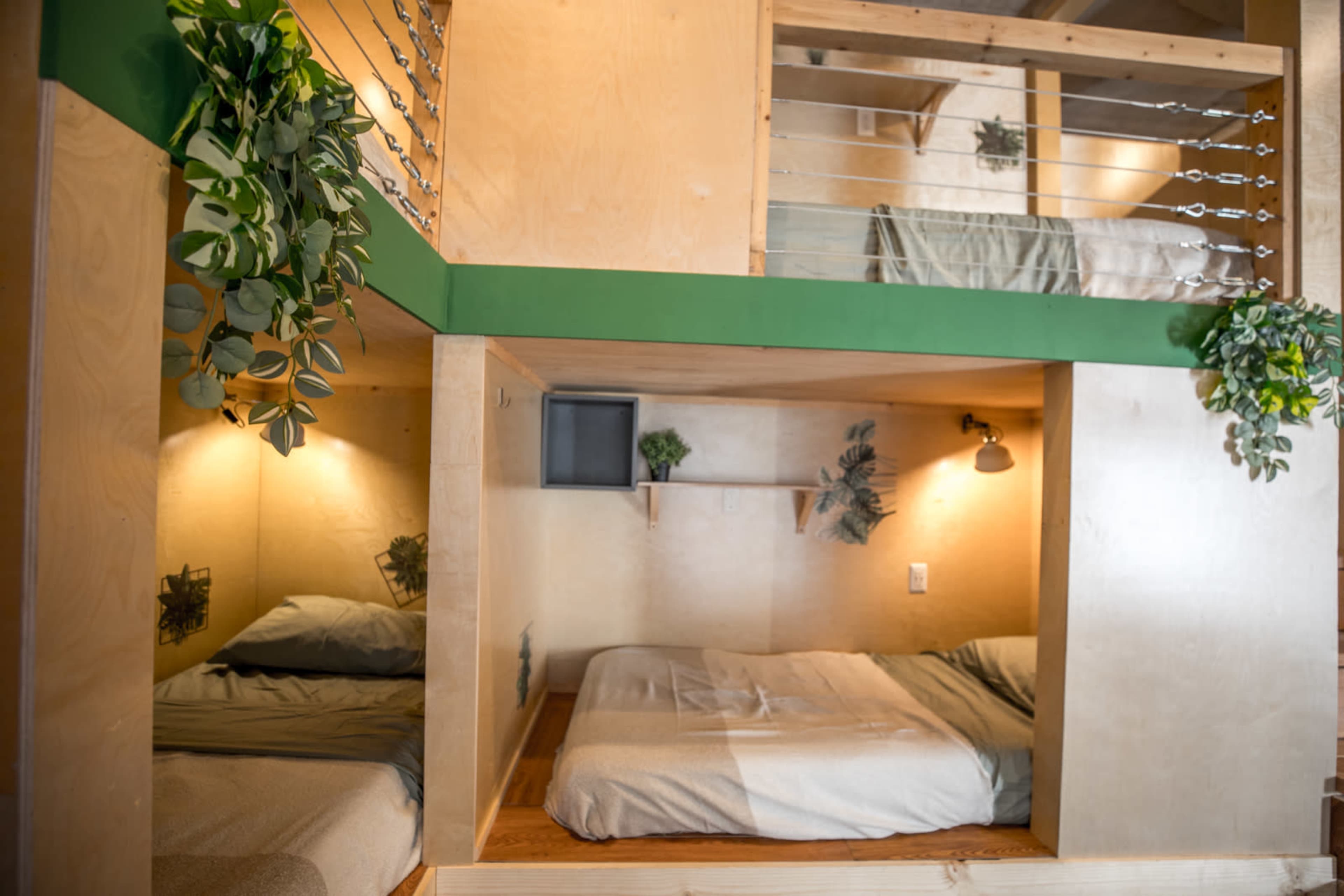 The image shows a modern, multi-level sleeping space with two separate sleeping areas, each featuring a bed and wooden accents.