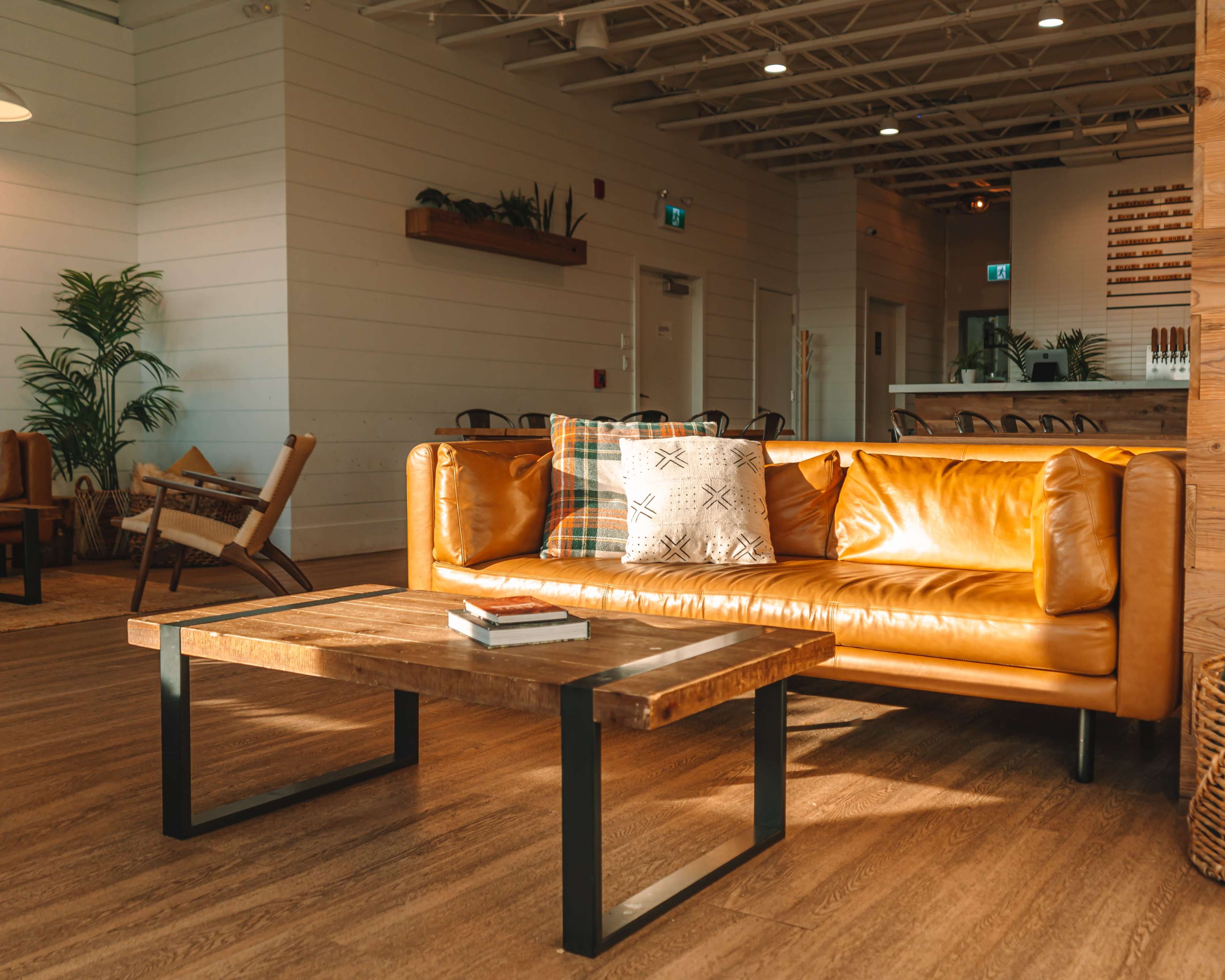 A bright, modern indoor space with a yellow leather sofa, a wooden coffee table, and a light-colored wooden floor.