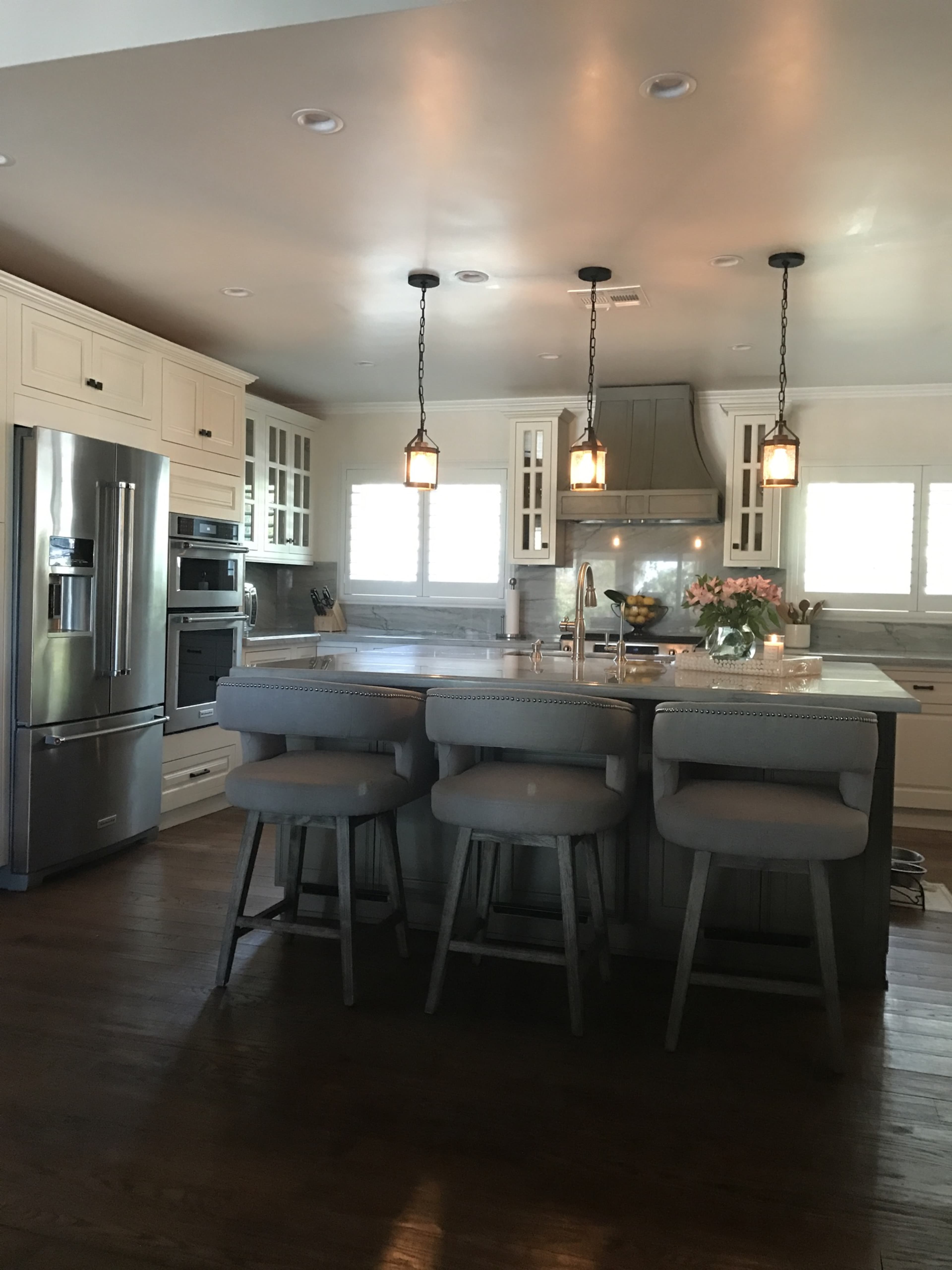 A modern kitchen featuring a central island with seating, stainless steel appliances, and pendant lighting.