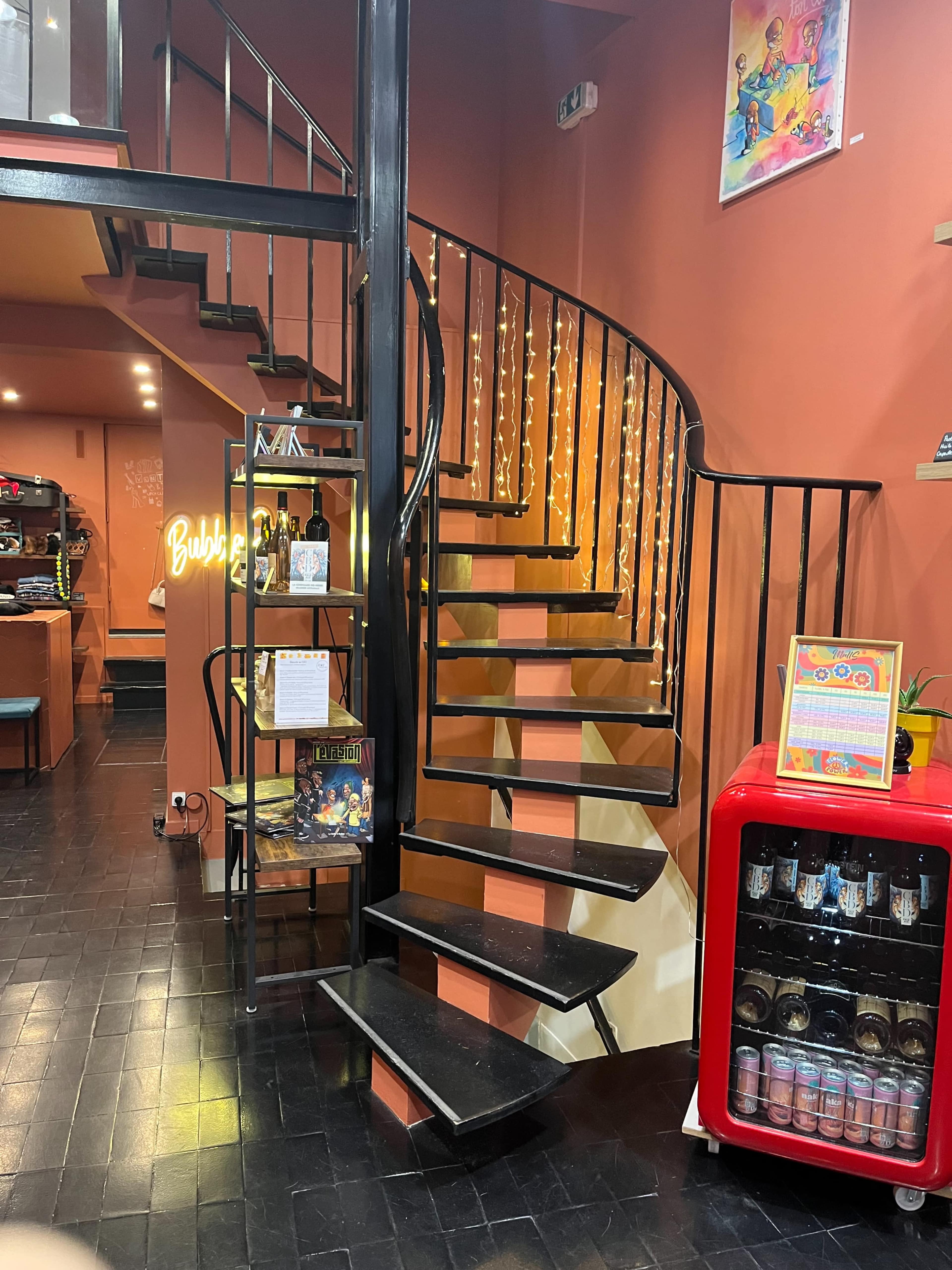 A spiral staircase alongside a wall with warm-colored paint and decorative string lights.