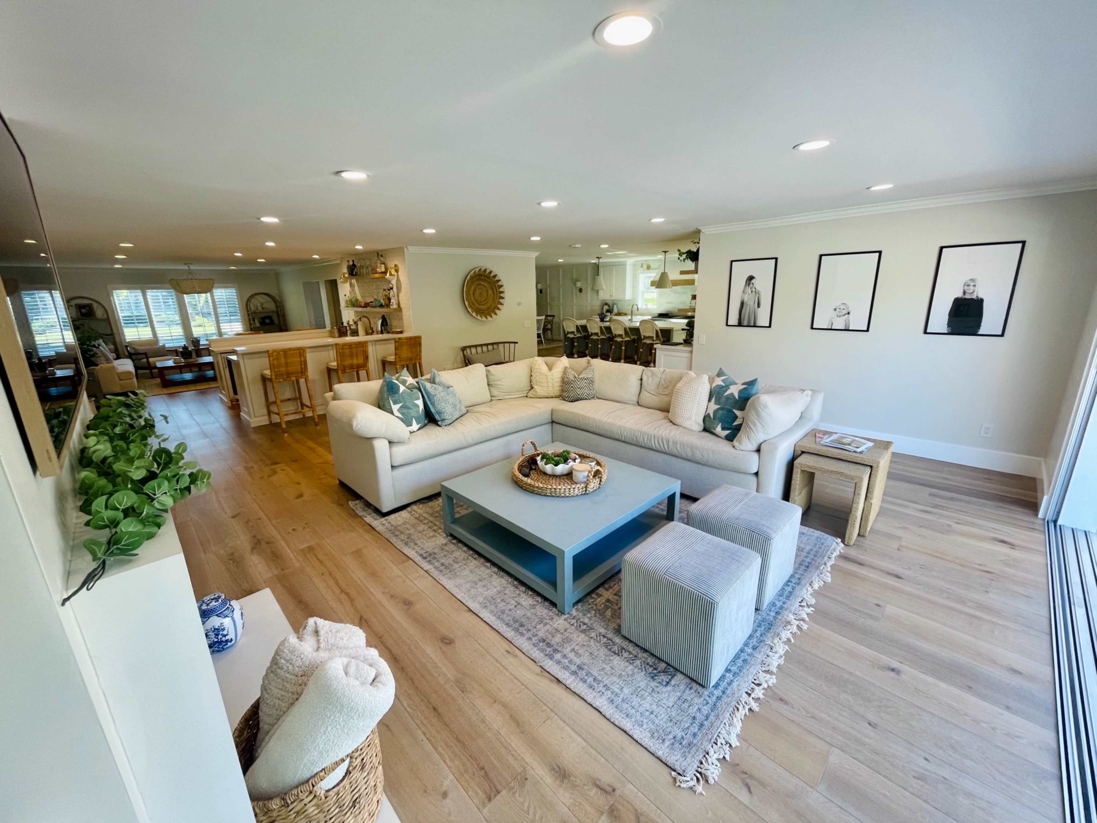 The spacious living room features a large sectional sofa, a coffee table, and several decorative elements, with an open layout connecting to a dining area and kitchen.