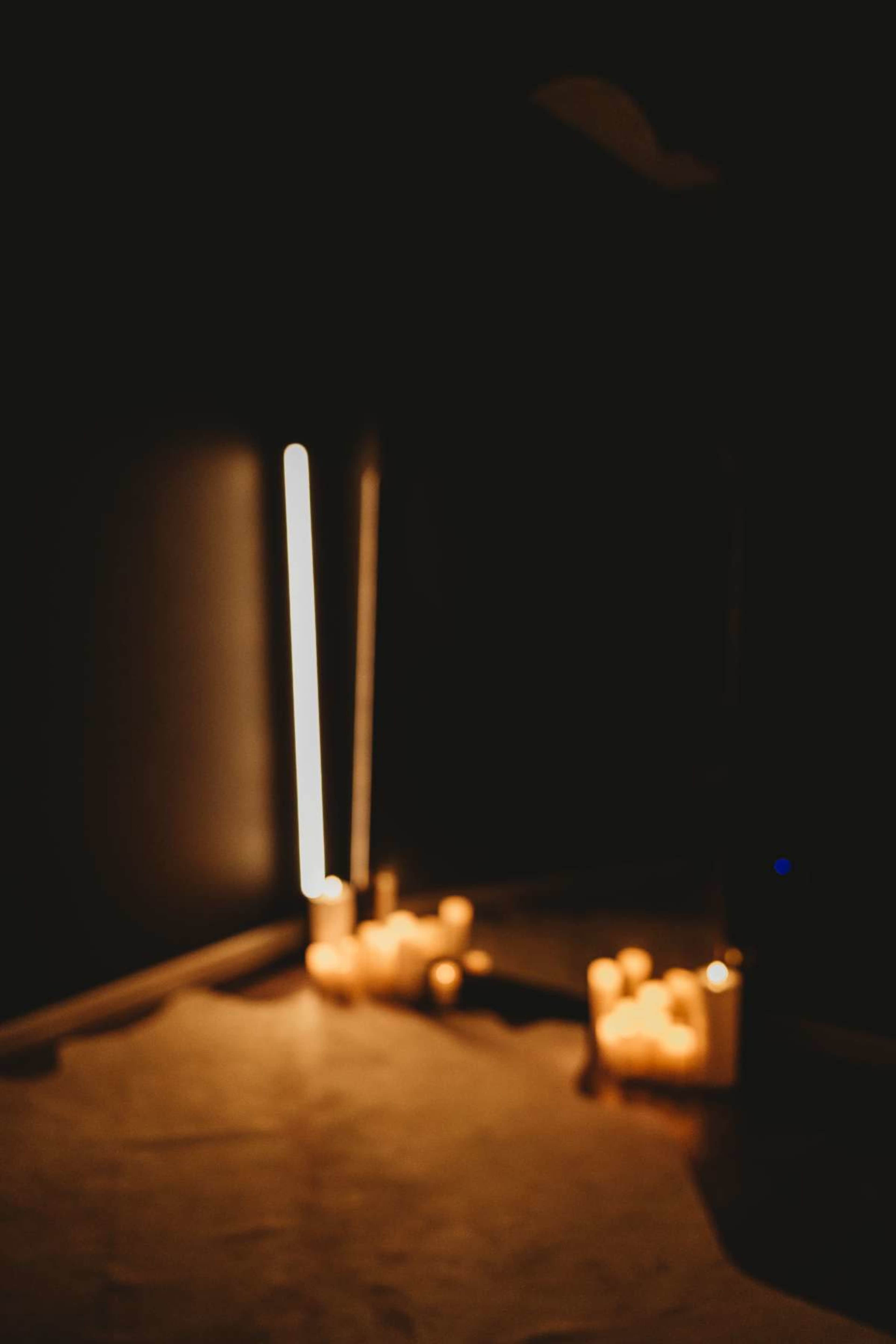 A dimly lit scene features a glowing light strip and several lit candles on the floor.