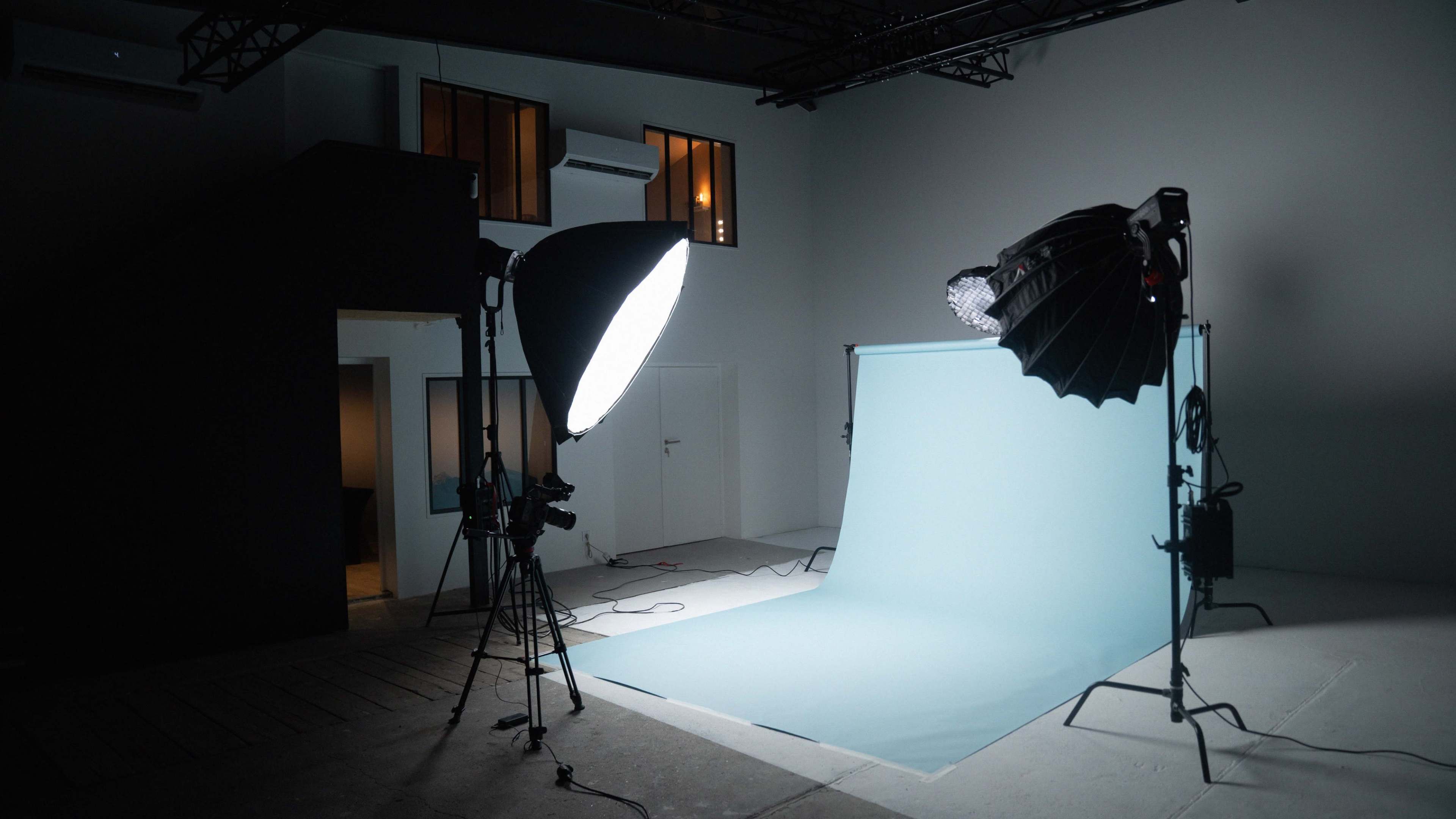 A photography studio with a light setup and a blue backdrop.