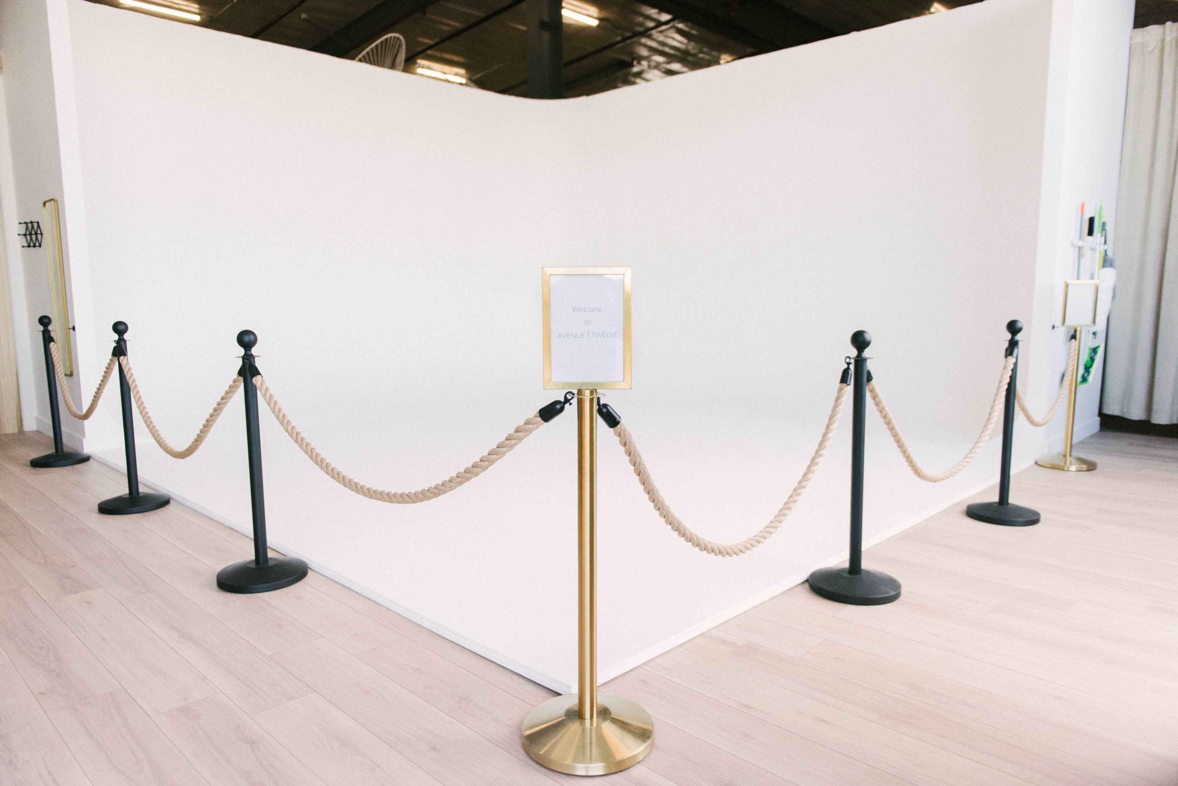 A white backdrop area surrounded by black stanchions and a rope barrier, with a sign indicating "Welcome" at the entrance.