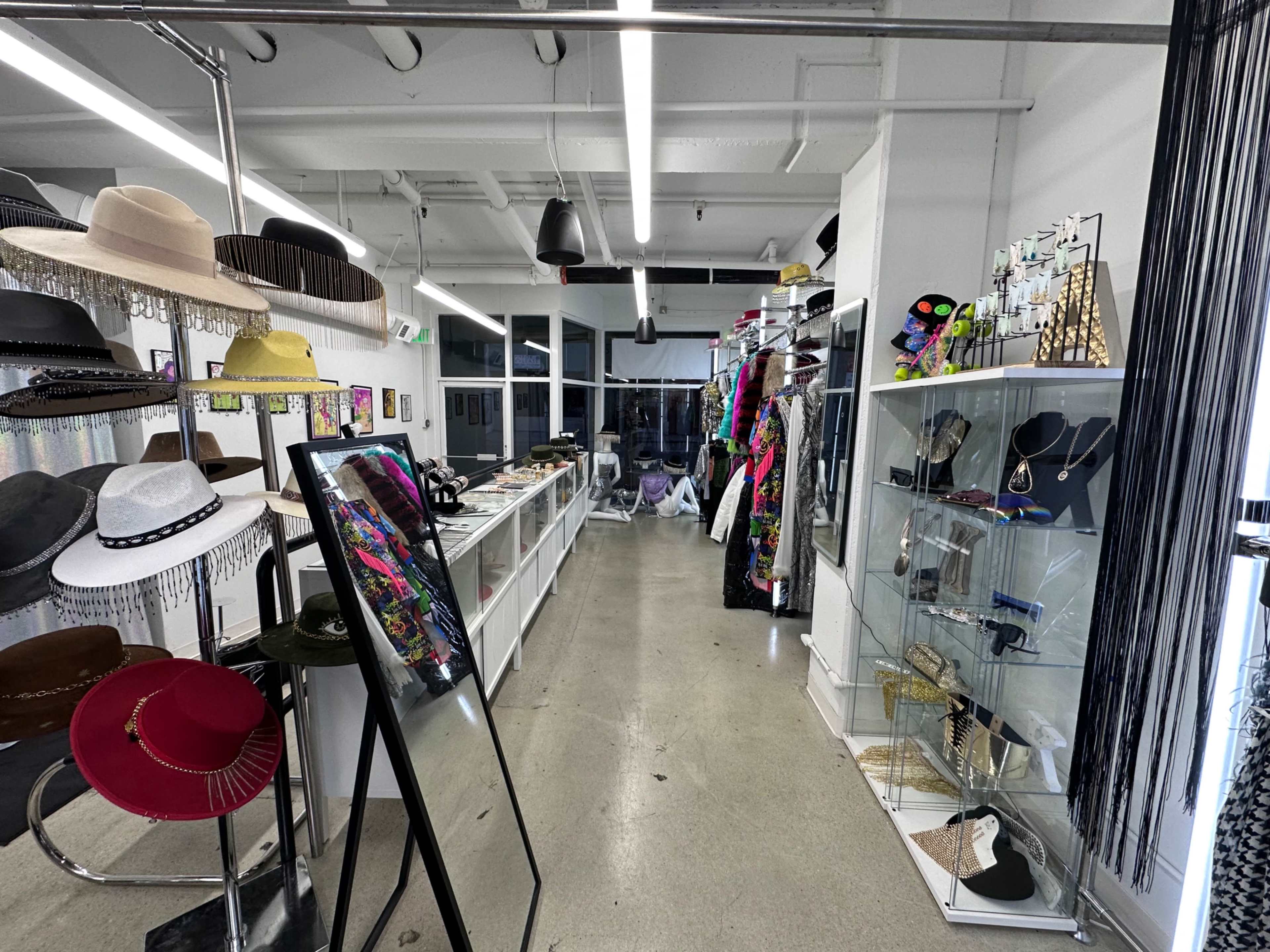 The image shows an interior view of a boutique filled with hats, jewelry displays, and a mirror along the walls.