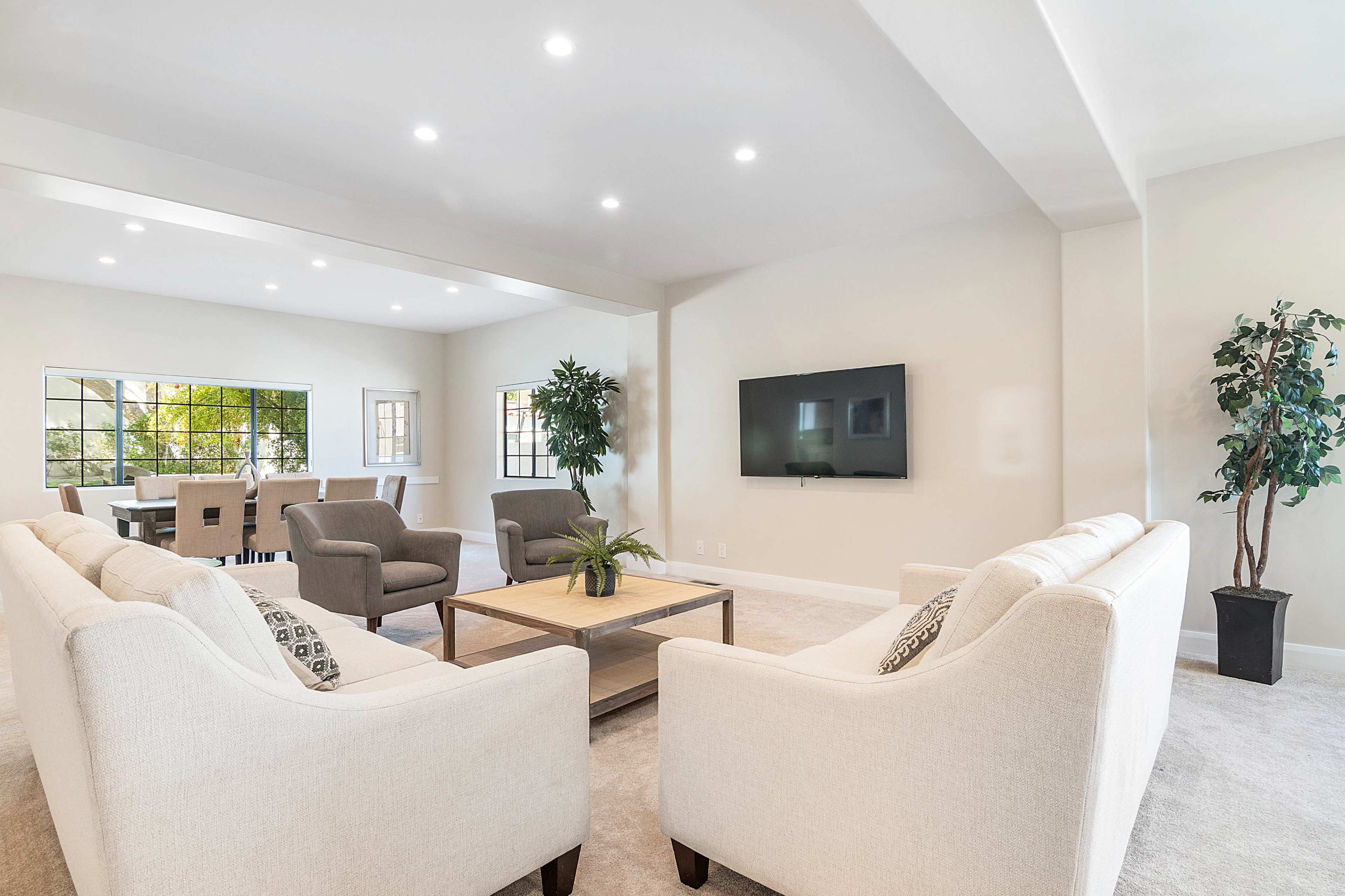 The image shows a bright, open living room with two light-colored sofas facing each other across a coffee table.