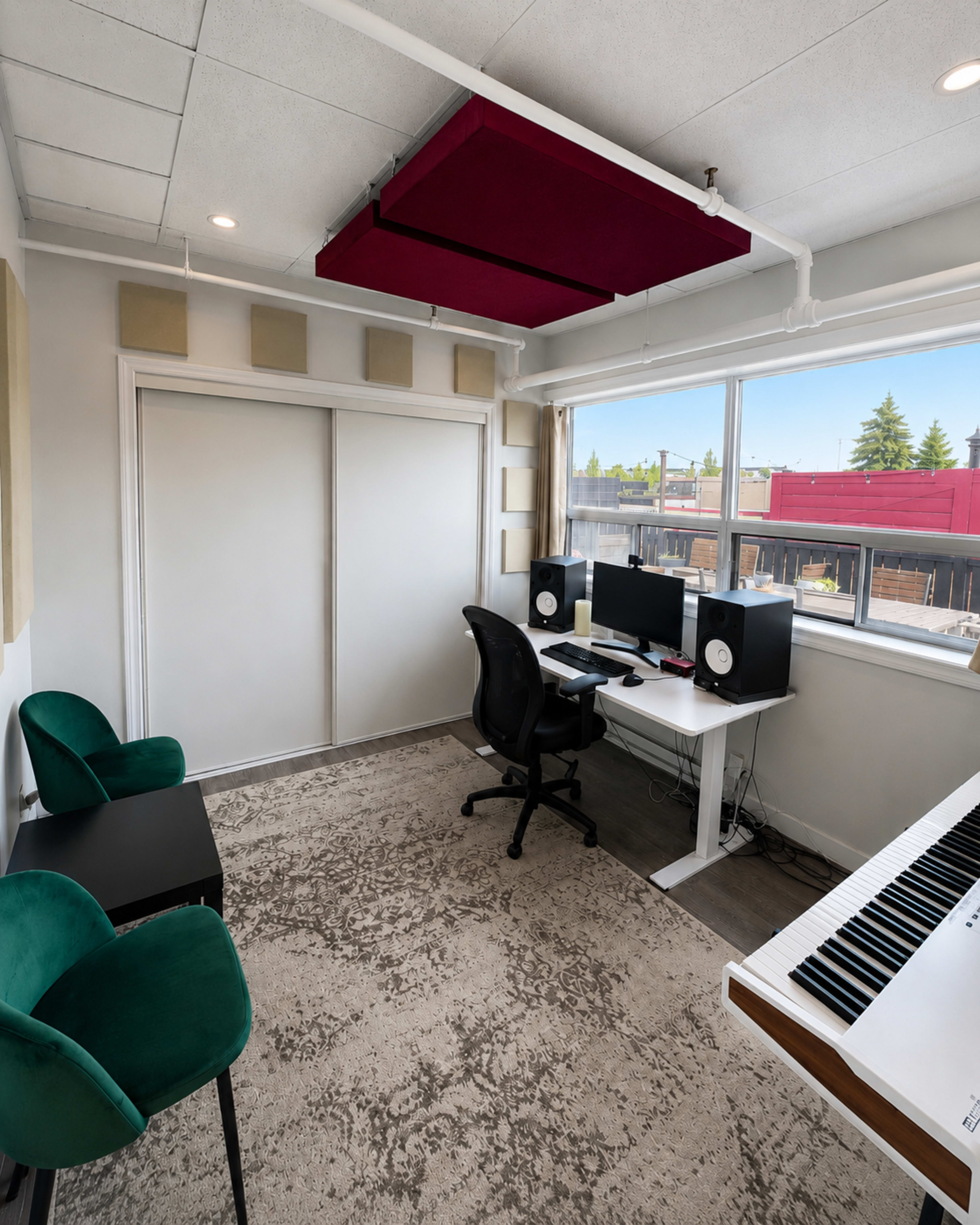 The image shows a modern workspace with two green chairs, a desktop computer setup with speakers, and a keyboard, all in a well-lit room.
