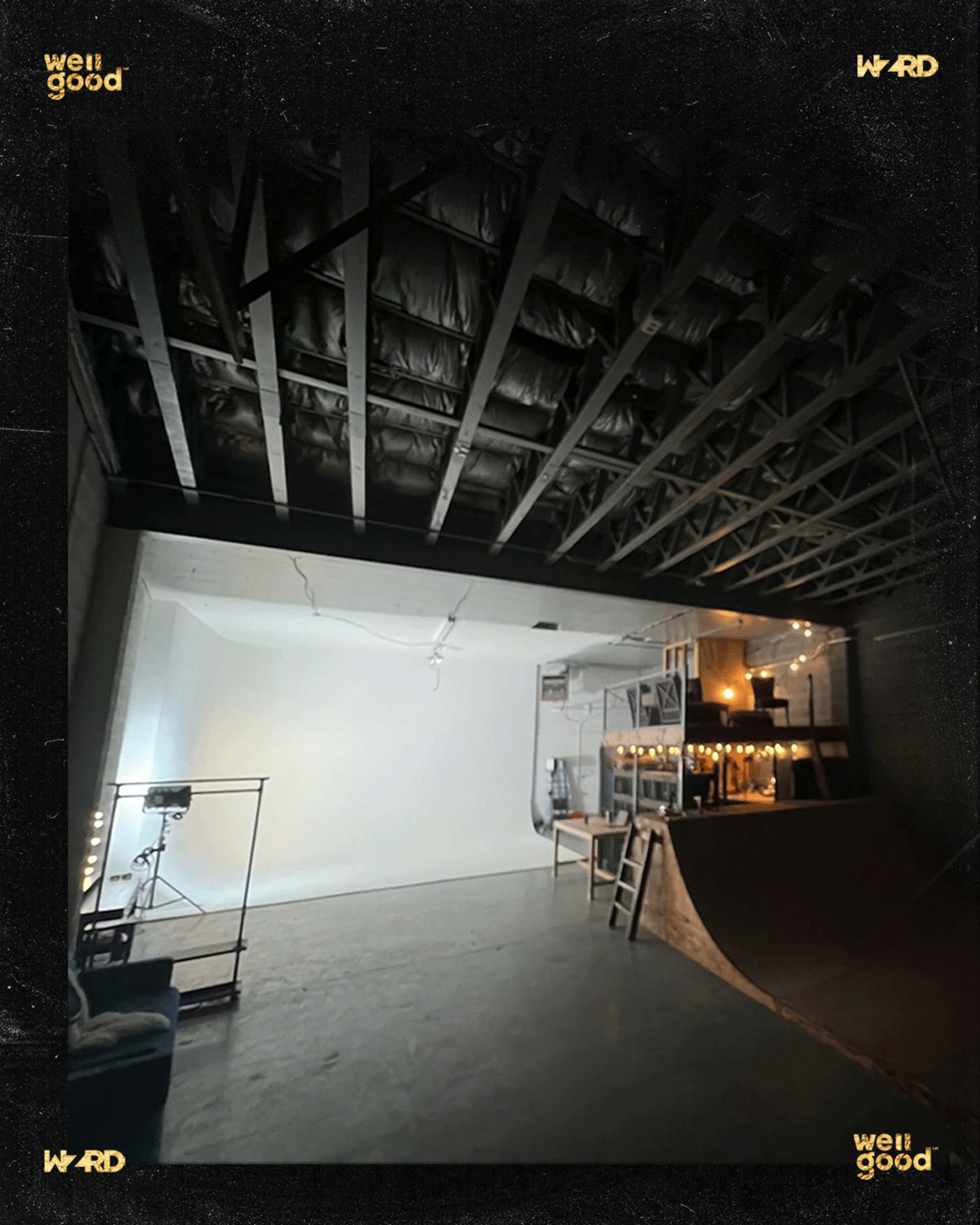 An empty studio space featuring a ramp on one side, a white backdrop, and various equipment arranged along the walls.