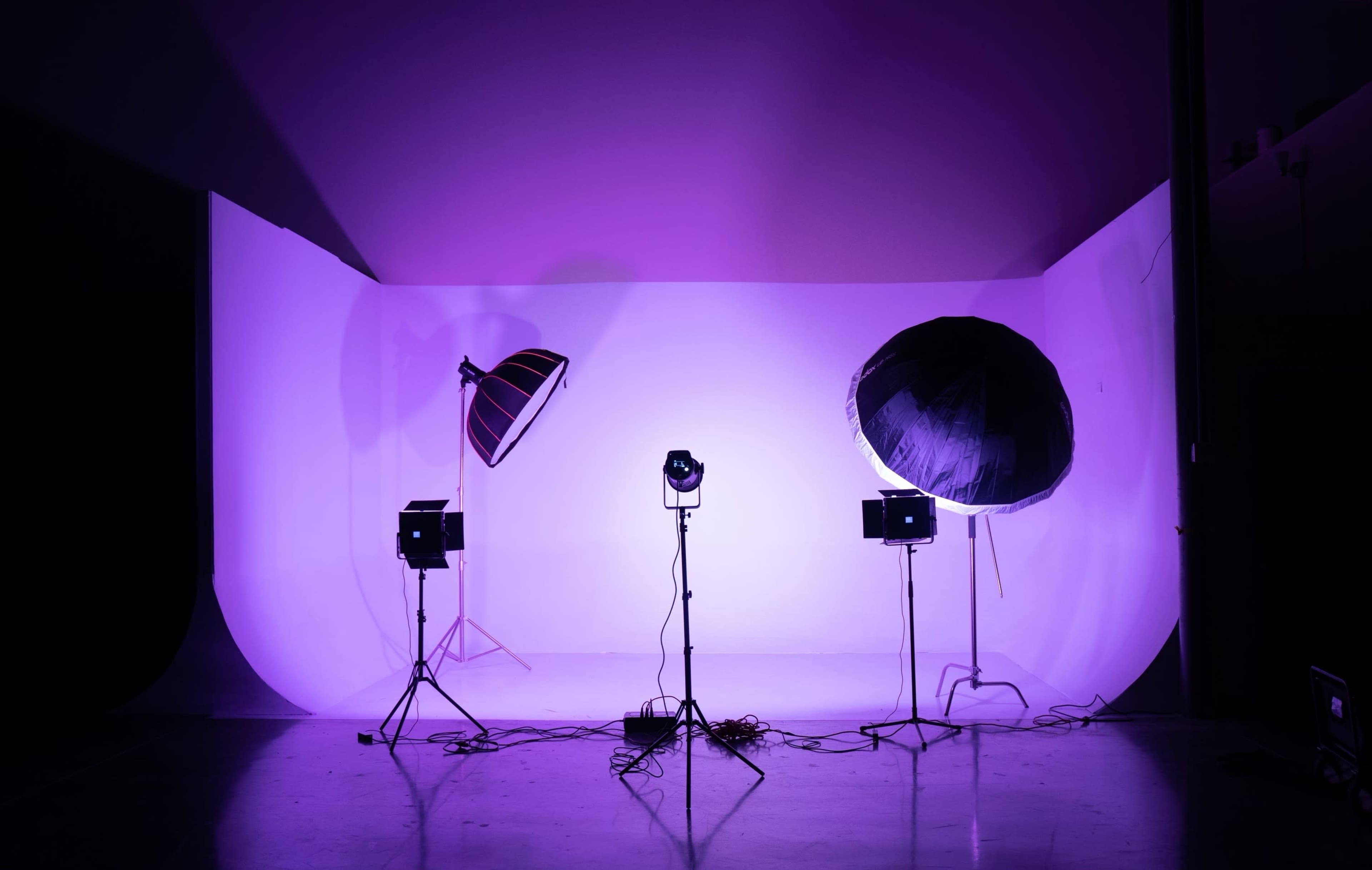 A photography studio with three lighting setups on a purple backdrop.